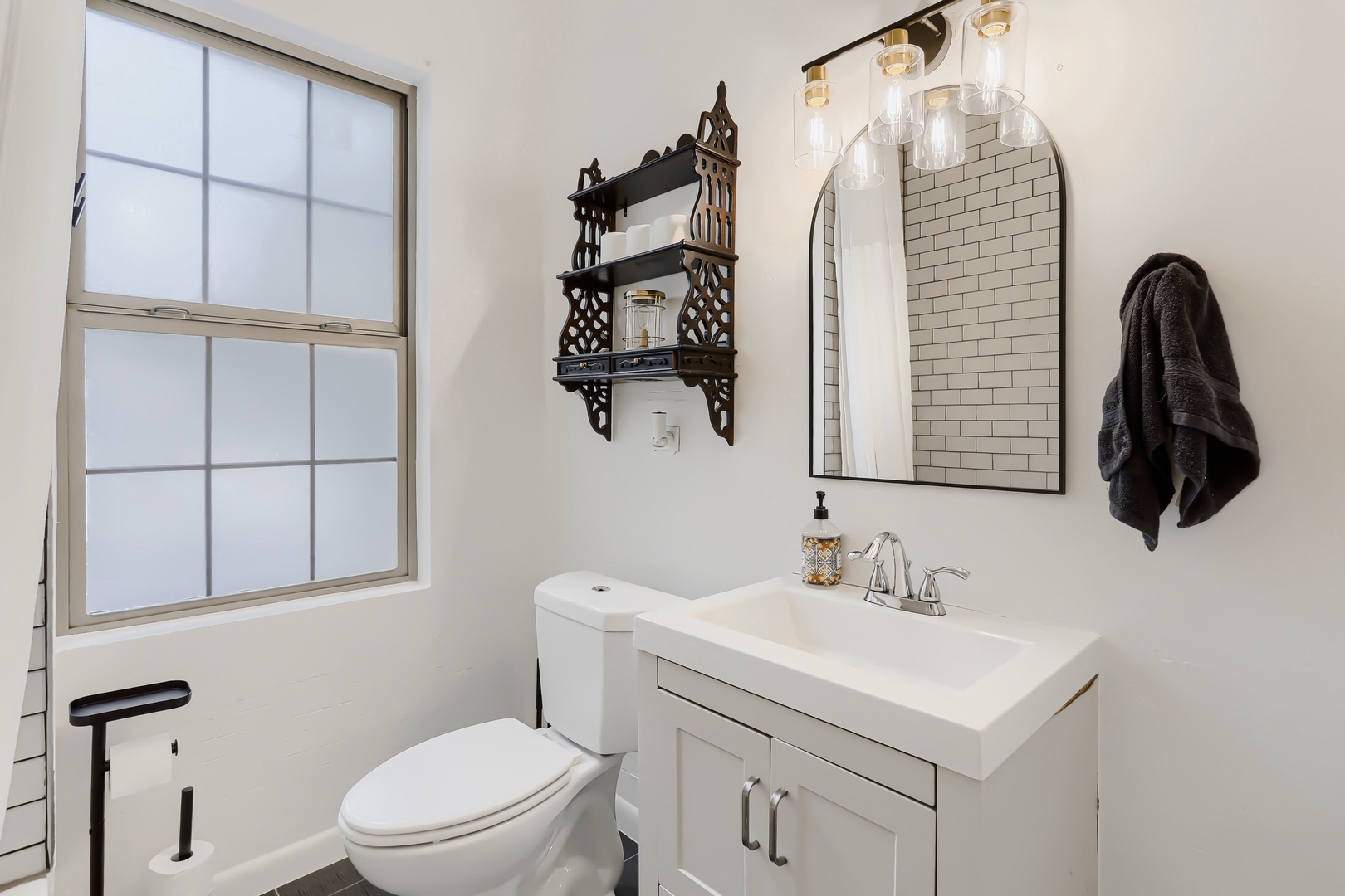 Refresh in your bright, modern bathroom featuring subway tile, a stylish arched mirror, and thoughtful touches like a vintage decorative shelf. Crisp white finishes and natural light create a clean, spa-like retreat after your adventures.