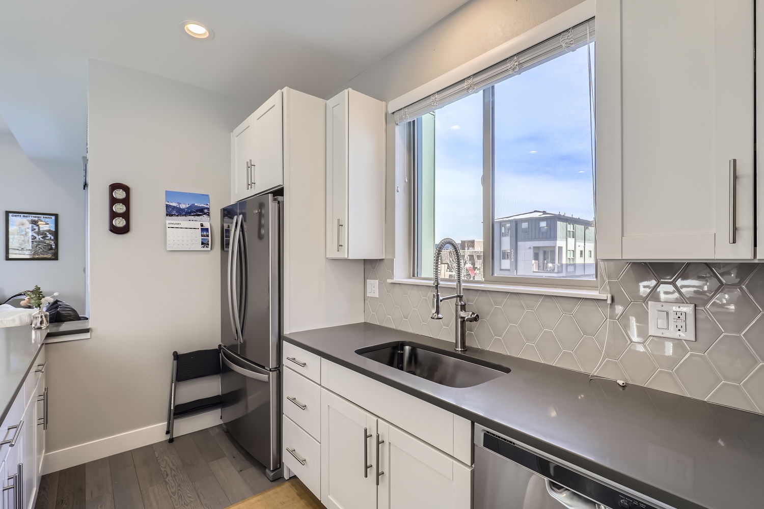 This stylish kitchen is yours to explore, with sleek modern appliances, crisp countertops, and a geometric tile backsplash that catches the light.