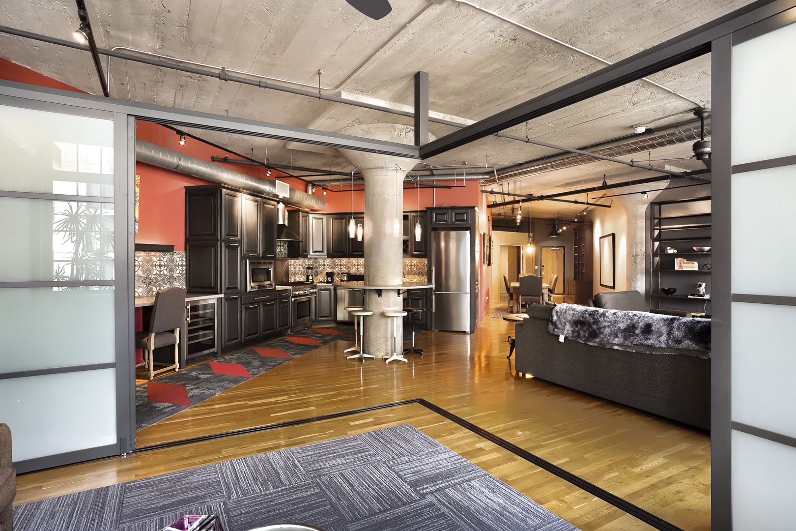 Step into this industrial-chic loft where soaring concrete ceilings and gleaming hardwood floors create an open, airy retreat. The bold accent walls and sleek kitchen invite you to feel at home.