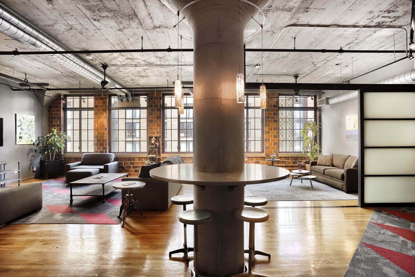 A spacious industrial loft-style living area showcases exposed brick walls, polished hardwood floors, and abundant natural light—inviting you to relax in this stylish urban retreat.