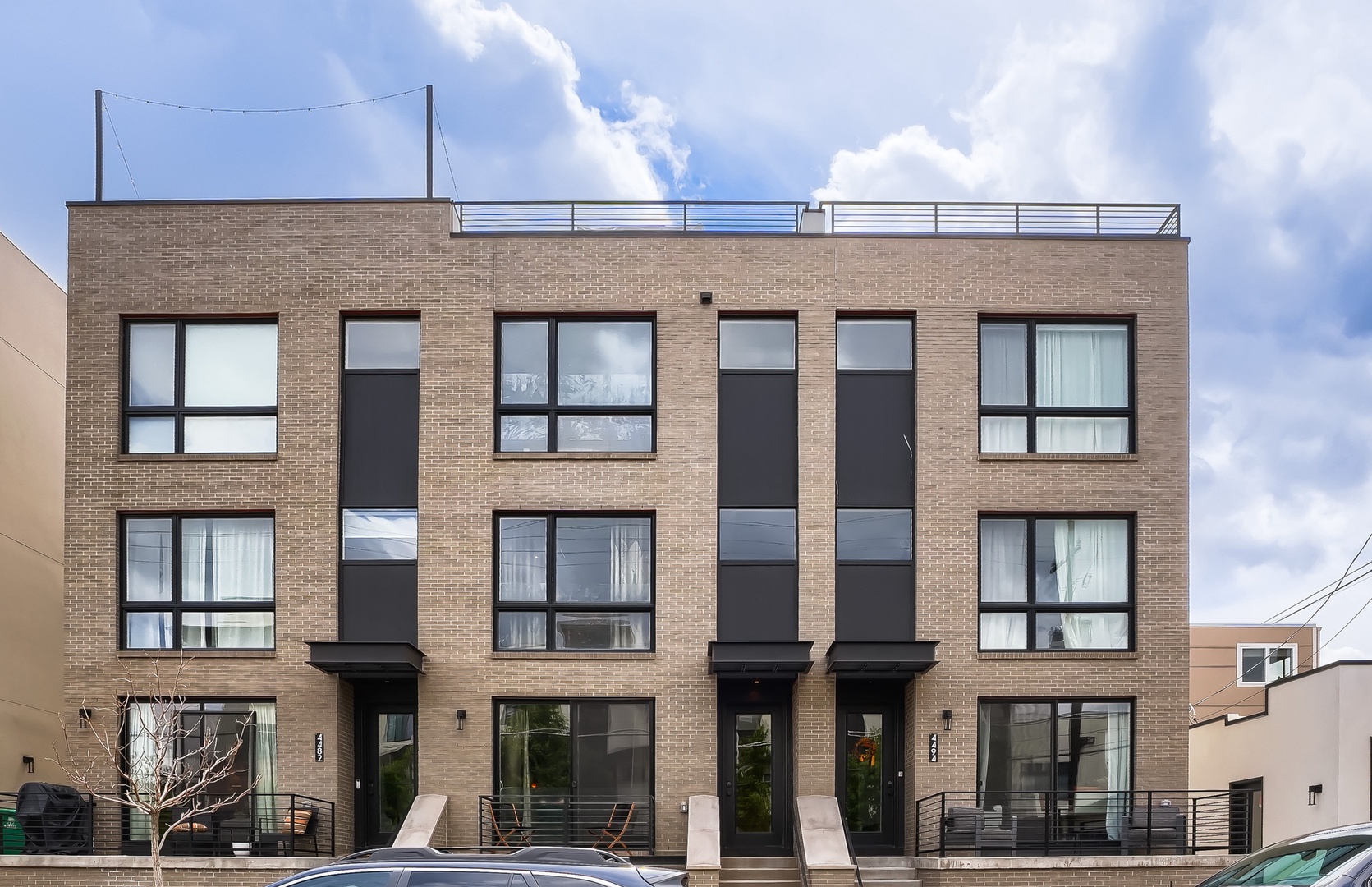 A modern urban property featuring contemporary brick architecture with a private rooftop terrace and balcony spaces for enjoying city life.