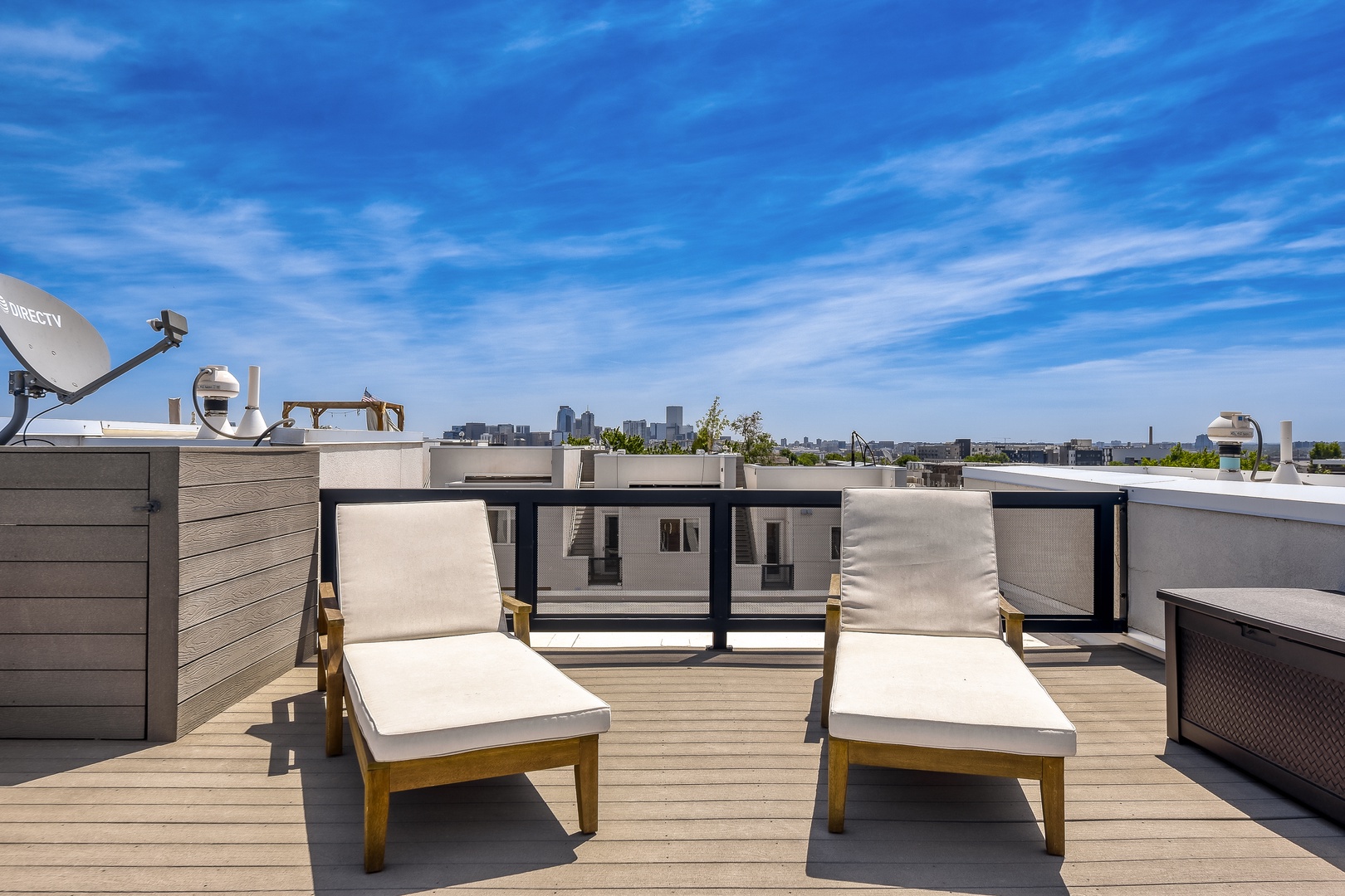 Private rooftop deck with two lounge chairs overlooking the city skyline—a perfect spot to soak in the sun and enjoy panoramic urban views from your own exclusive retreat.