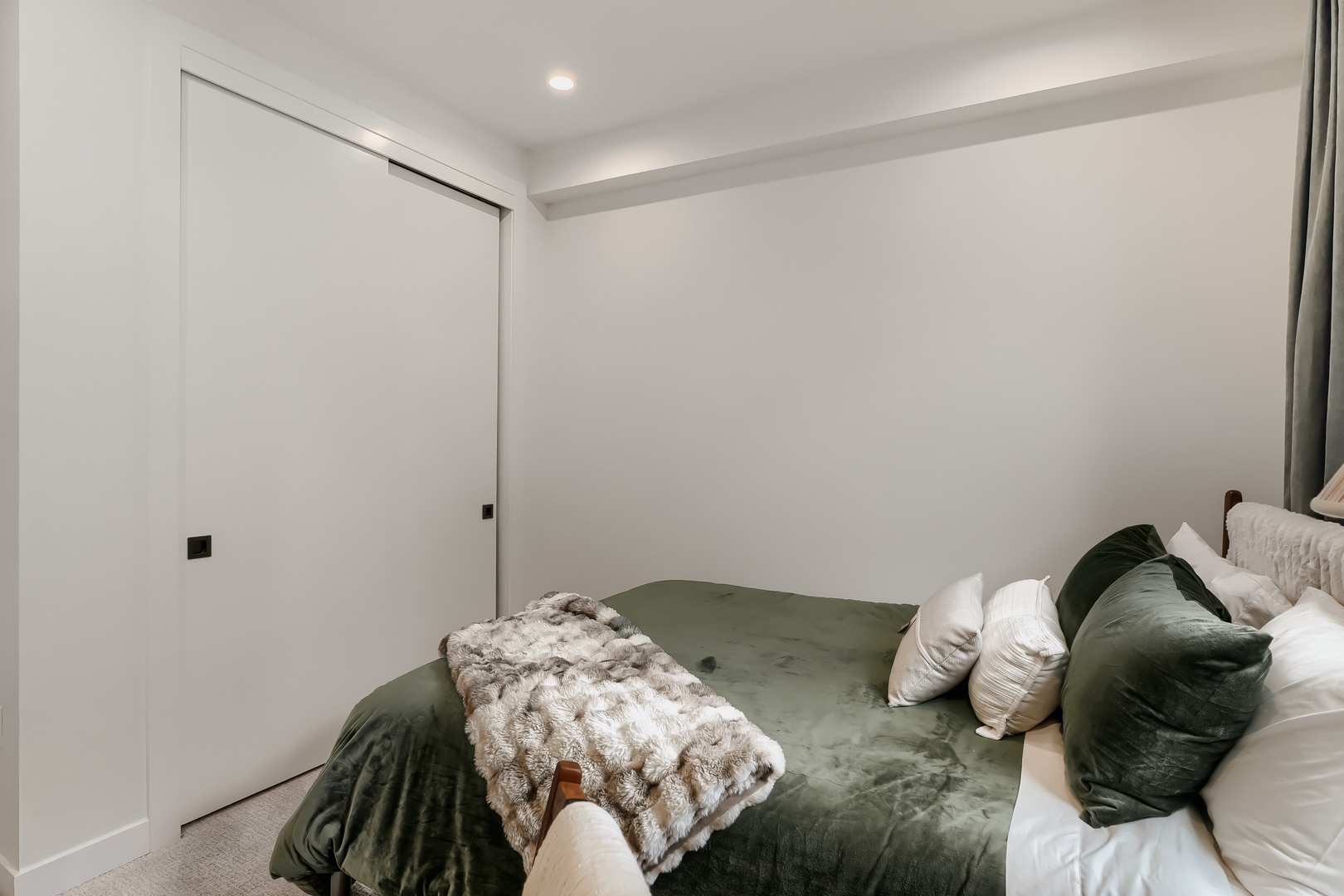 Slip into this serene bedroom where crisp white walls and soft textures create your perfect retreat. The plush sage bedding invites restful nights, while sleek built-in storage keeps everything tidy.