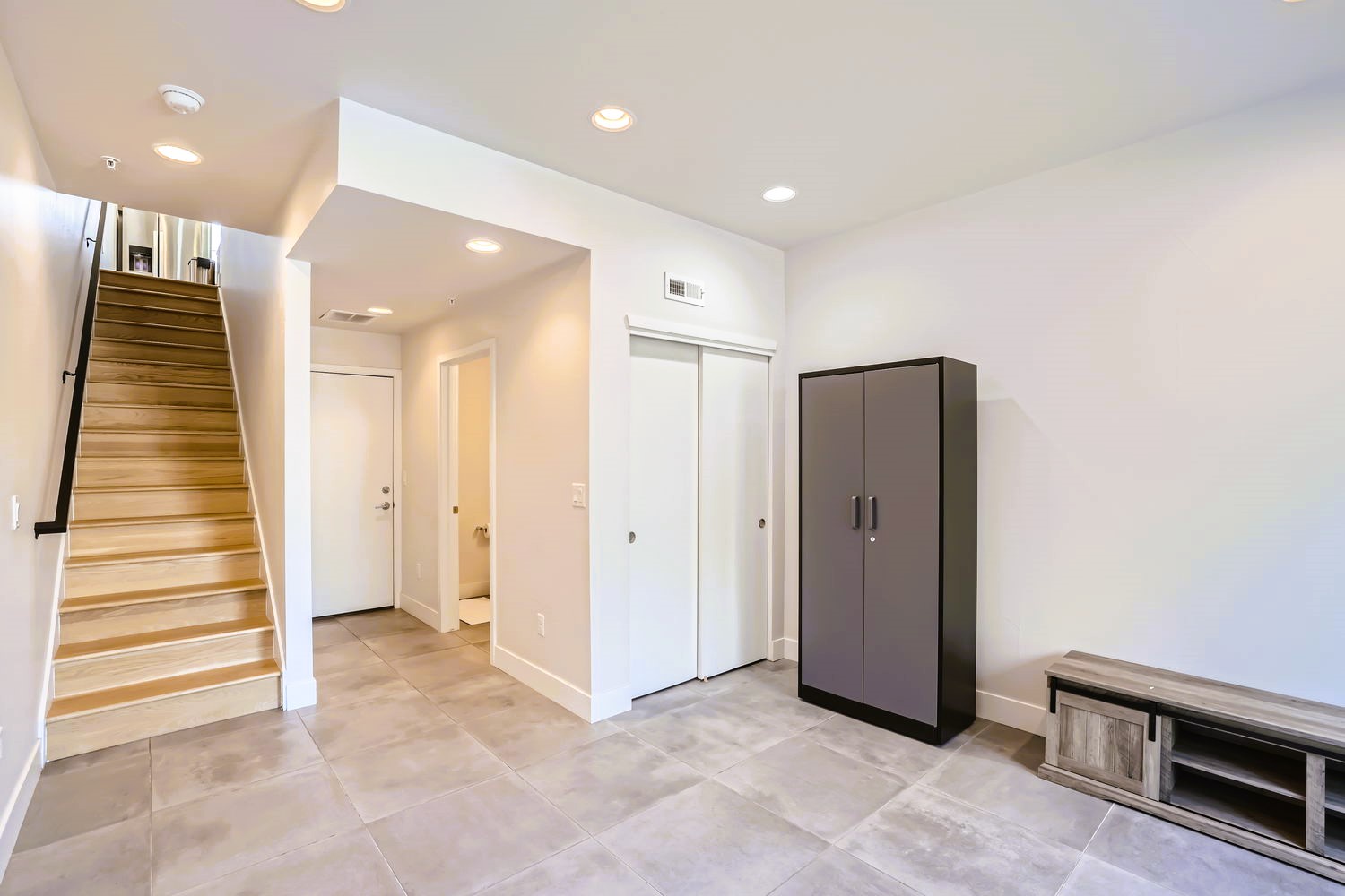 Step into your modern entry with sleek tile floors, stylish storage, and a striking wooden staircase that welcomes you home.