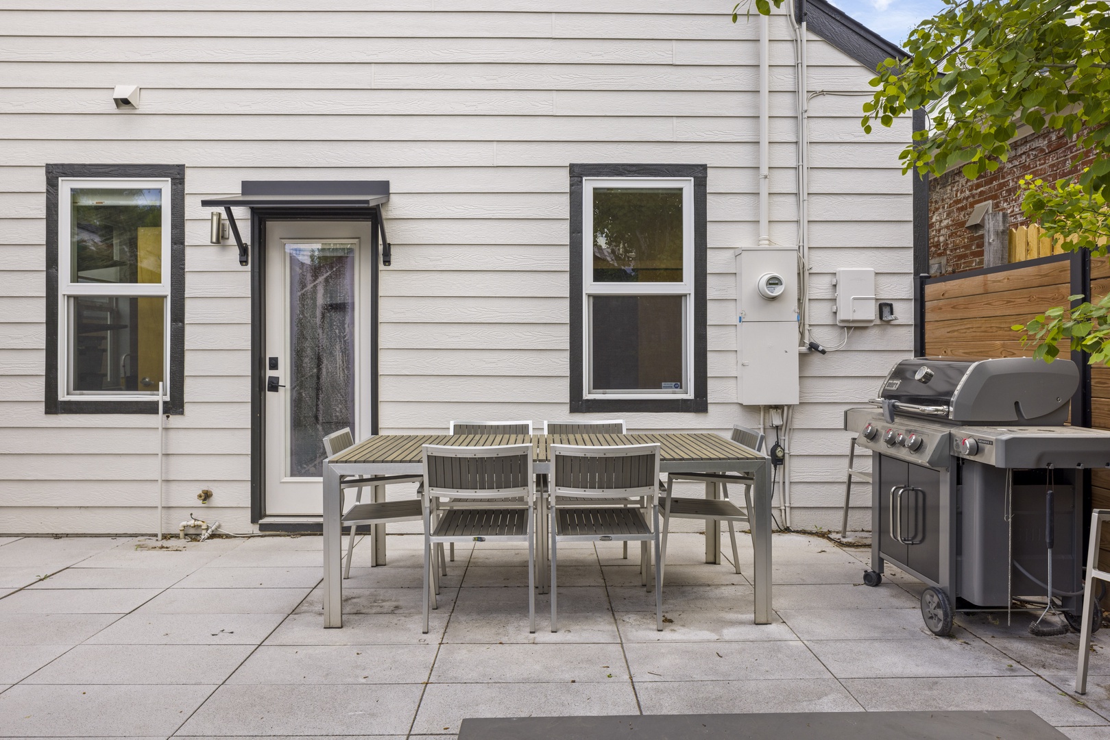 Step onto your private patio where al fresco dining awaits with a modern table set and premium BBQ grill ready for memorable outdoor meals.