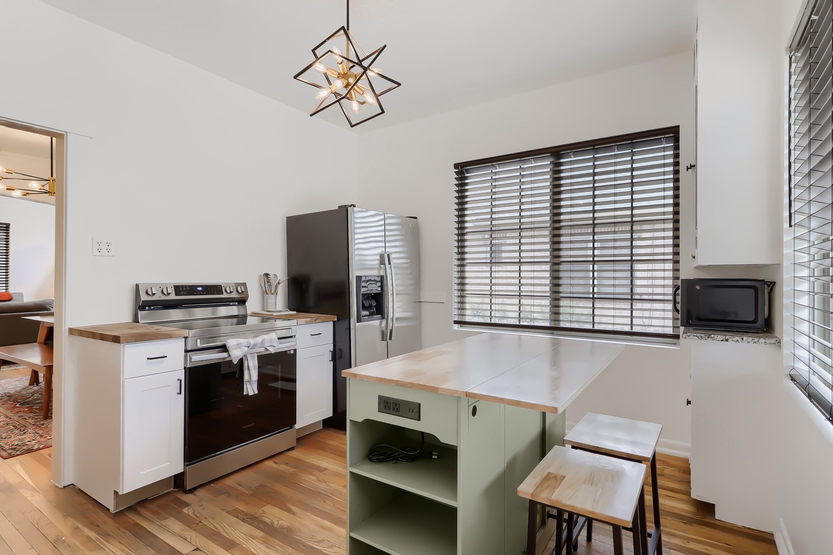 You'll love preparing meals in this bright, modern kitchen with its stylish island seating, stainless steel appliances, and warm wood countertops that invite your culinary creativity.