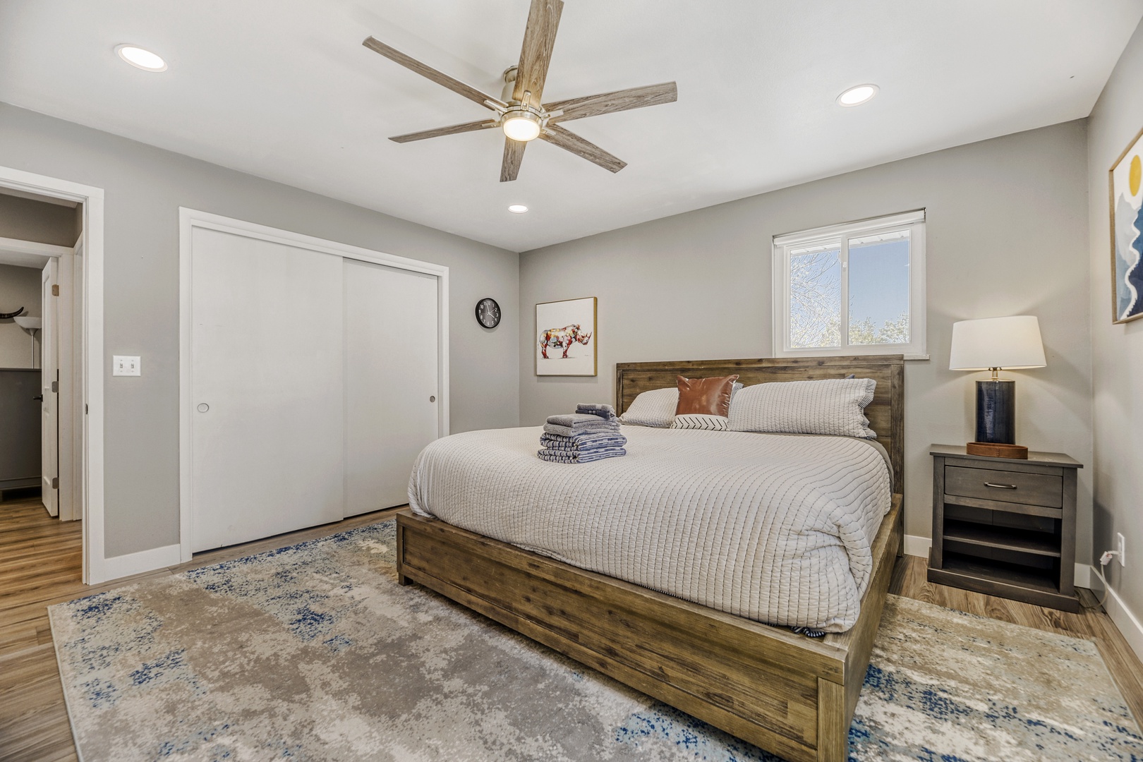 Relax in this serene bedroom featuring a plush bed with soft linens and rustic wood accents. Fresh towels await your arrival while natural light streams through the window.