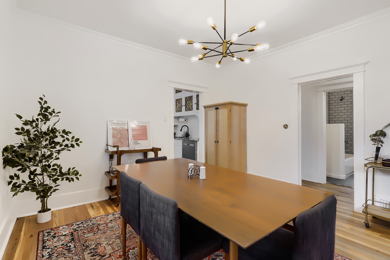 Gather around the warm wood dining table under a striking starburst chandelier—perfect for your morning coffee or evening meals together in this bright, inviting space.