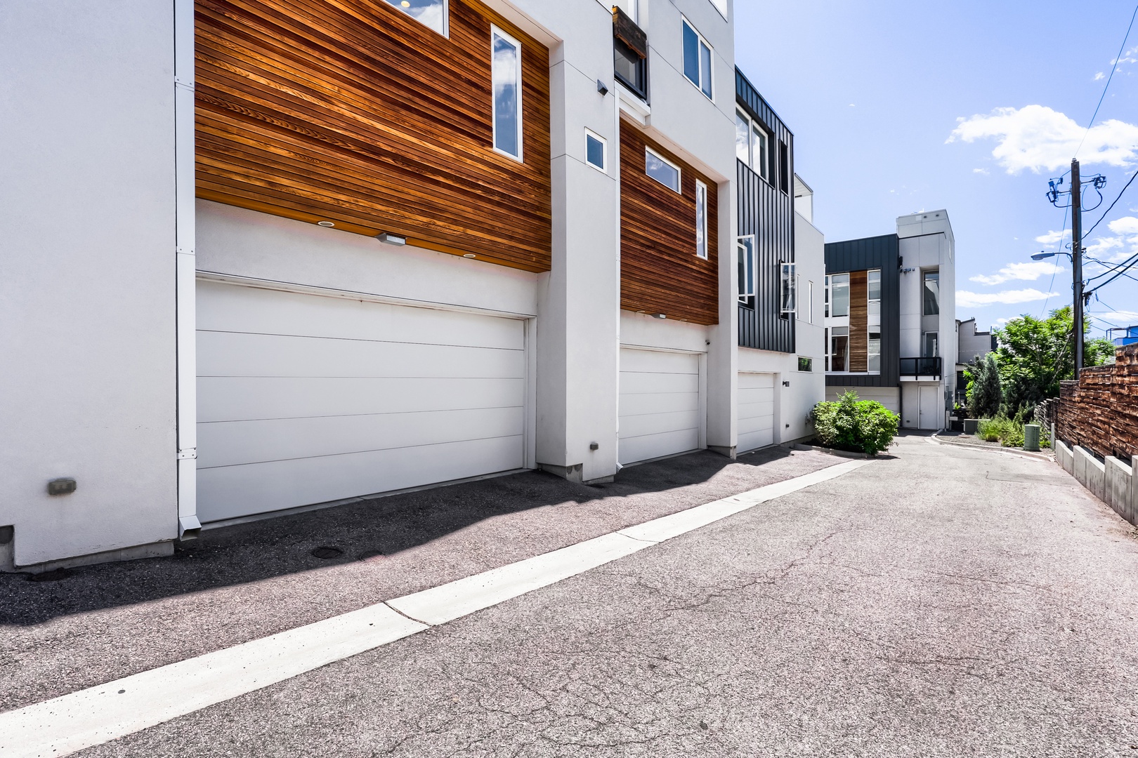 Modern townhomes with stylish wood accent panels and convenient street-level garage access line this quiet residential lane, offering privacy and easy parking for your stay.