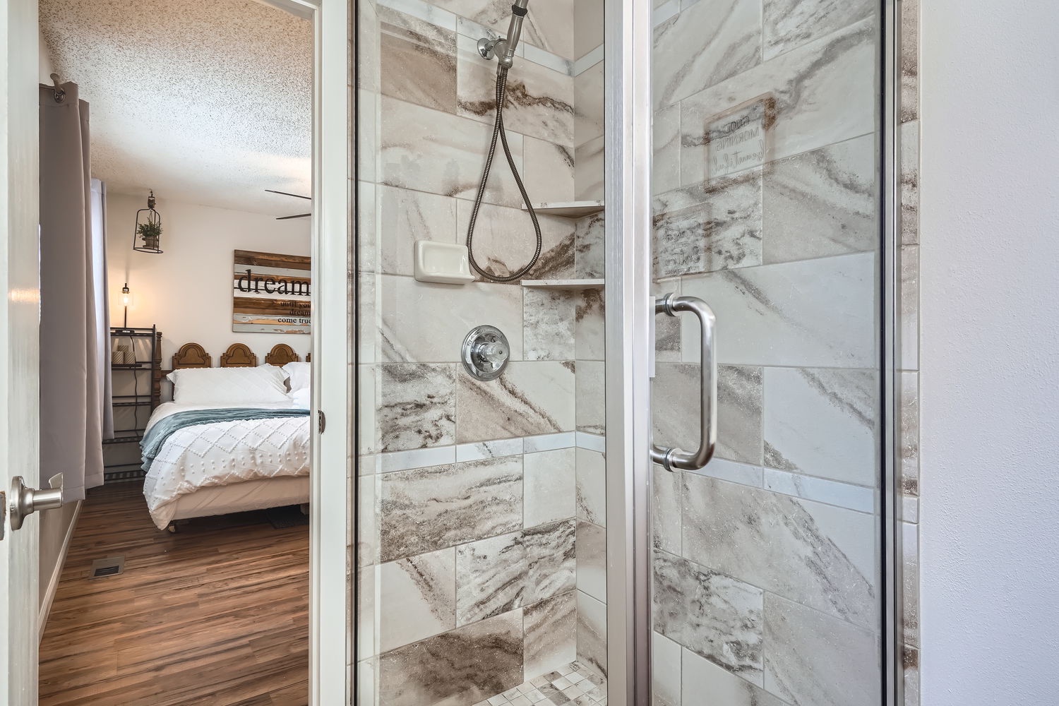 Your private en-suite shower awaits, featuring elegant marble-style tile and a modern glass enclosure—perfect for refreshing mornings before exploring the area.