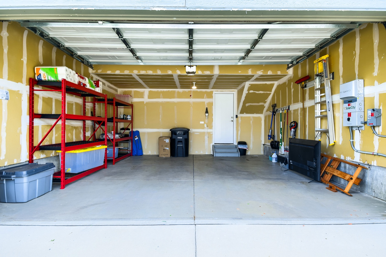 Spacious garage with organized storage shelving, providing convenient space for your belongings and easy vehicle access during your stay.