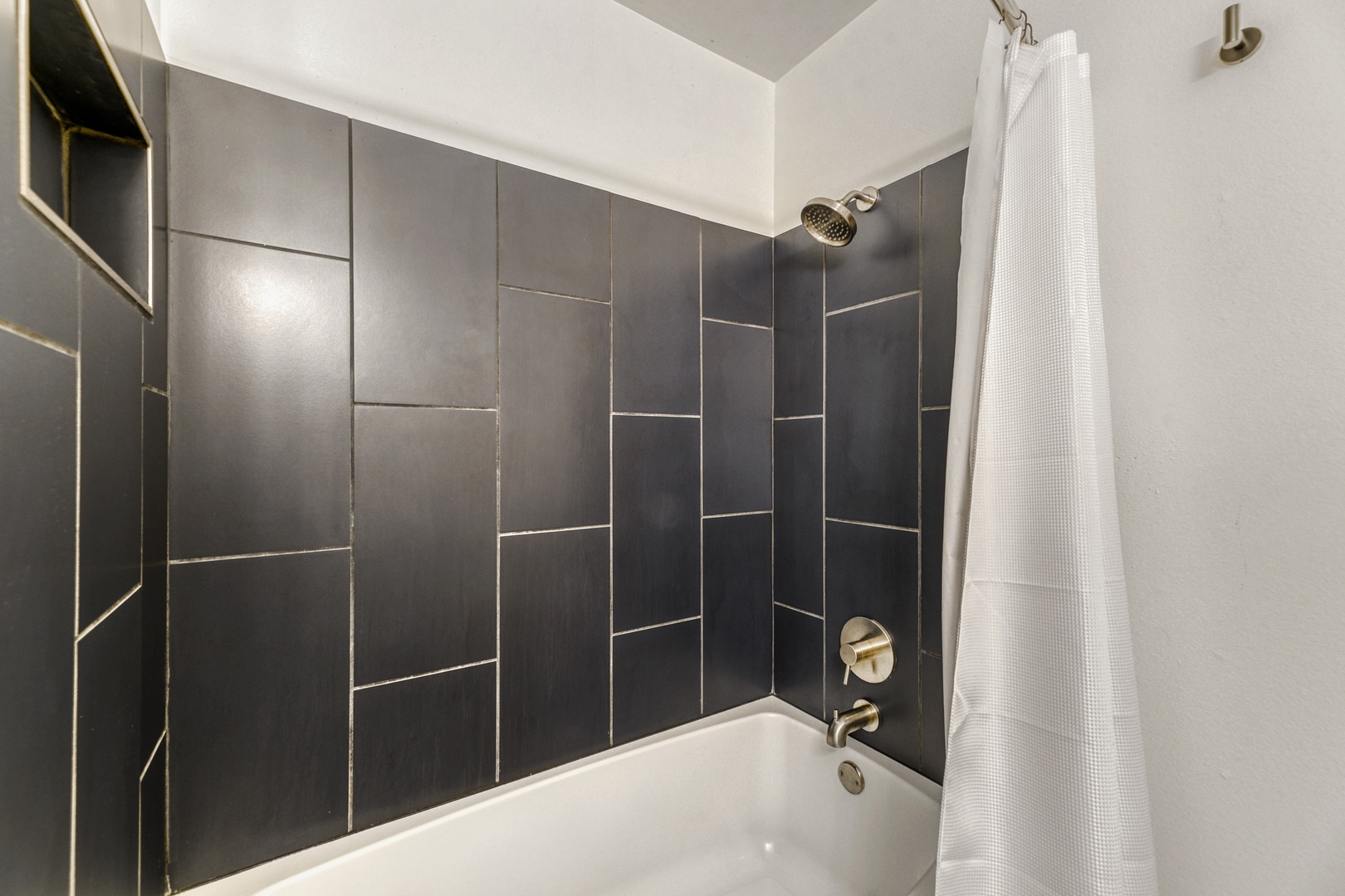 Refresh after your adventures in this sleek modern bathroom featuring a pristine tub-shower combo, chic gray tile, and brushed gold fixtures for your comfort.