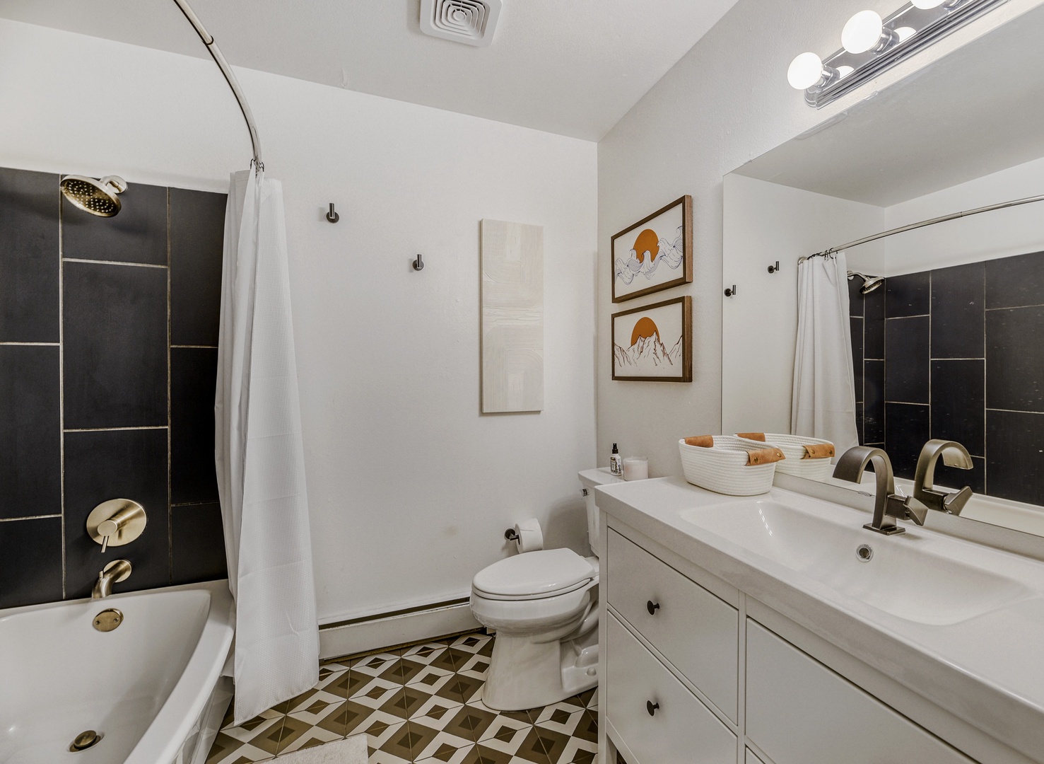 Step into your stylish bathroom with sleek black-tiled shower, modern vanity, and artistic mountain prints adding warmth. Fresh linens and thoughtful touches make this your personal retreat.