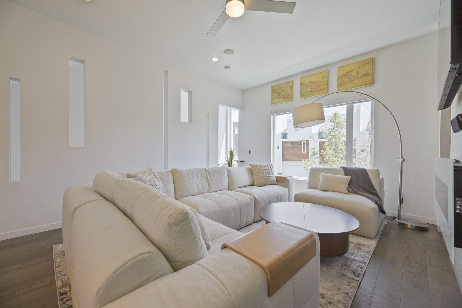Sink into plush sofas in this airy living room, where natural light floods through tall windows and a sleek arched lamp adds modern flair to your relaxing retreat.