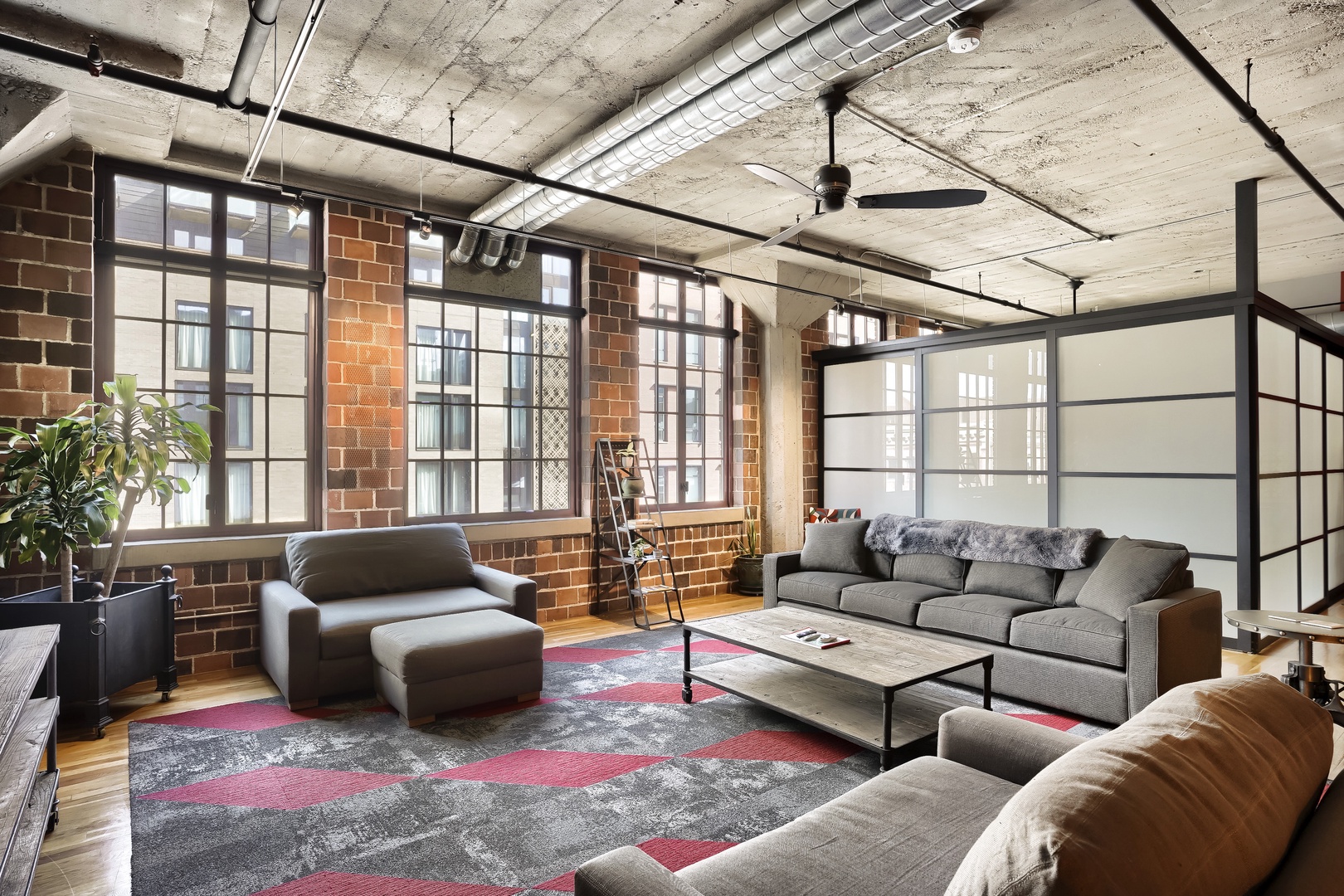 Step into a bright, industrial-chic loft where soaring ceilings, exposed brick walls, and floor-to-ceiling windows create a stylish, open retreat for unwinding in urban comfort.