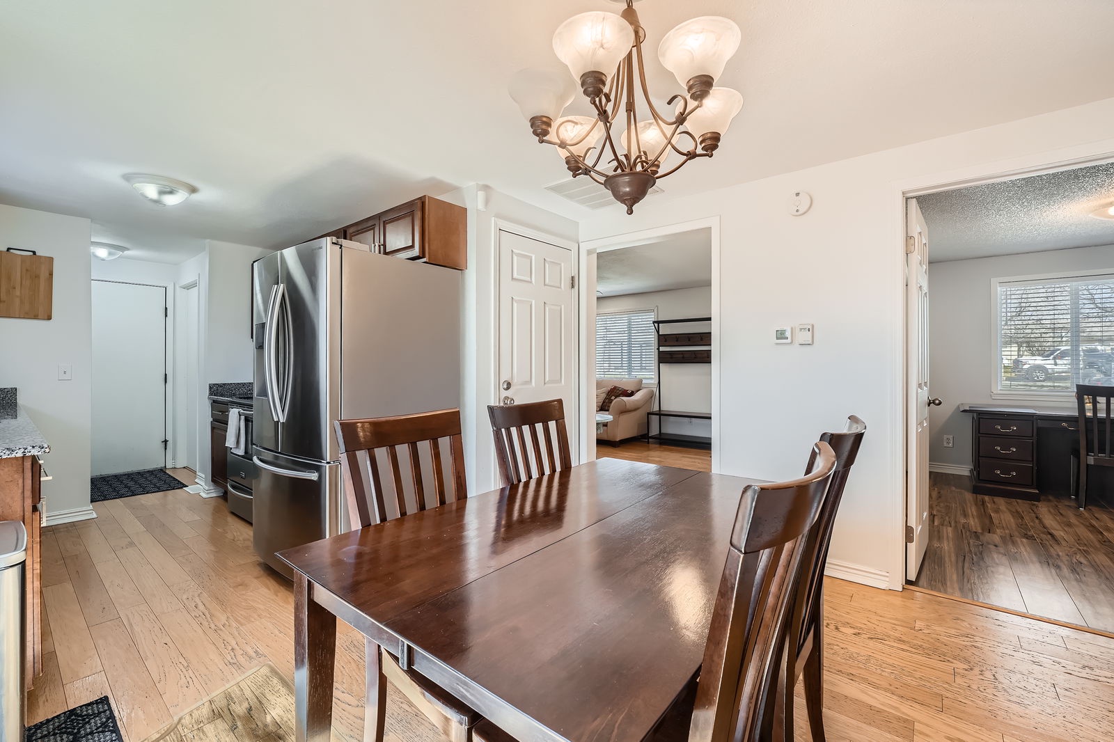 Gather around this elegant dining table for memorable meals under warm chandelier light, with modern kitchen just steps away.