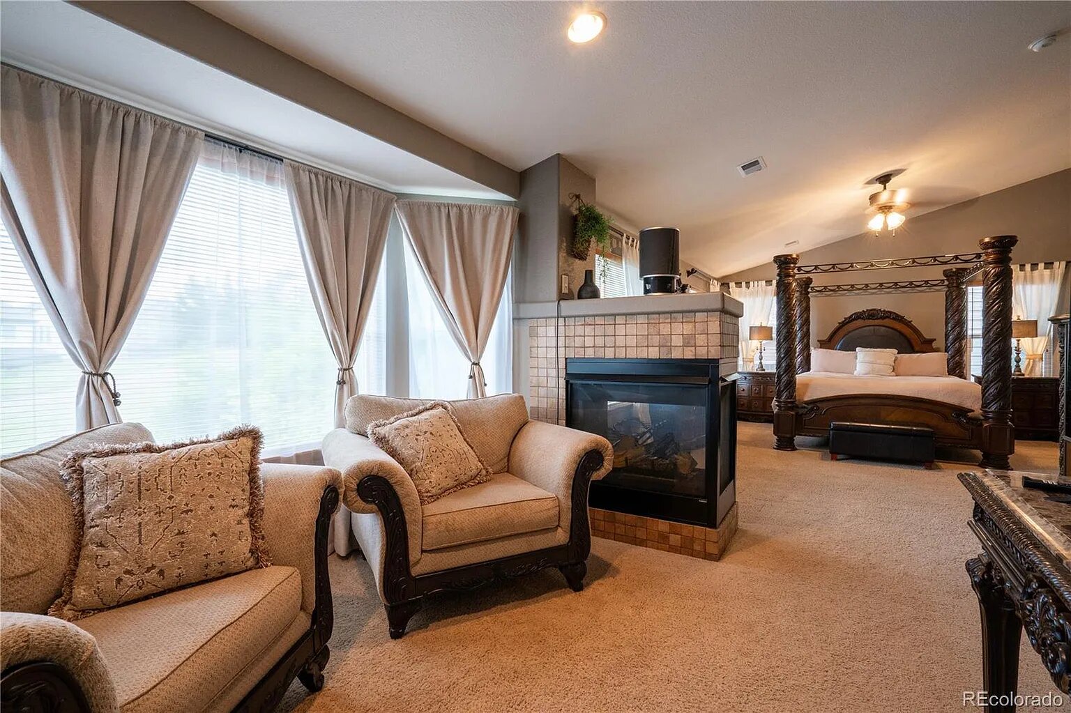 Unwind in your luxurious bedroom suite featuring plush seating, a warming fireplace, and elegant four-poster bed.