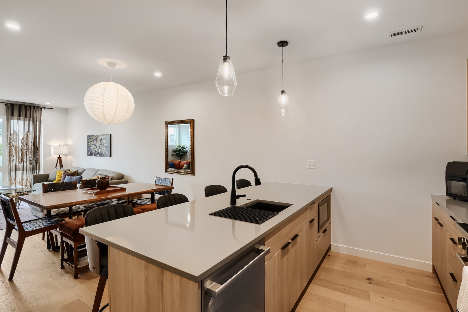 Gather in your open-concept living space with a modern kitchen island, inviting dining table, and cozy lounge area—perfect for preparing meals and relaxing together.