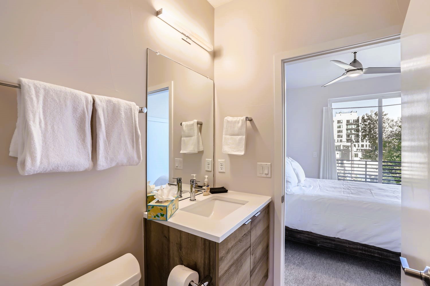 Your stylish bathroom features fresh towels and modern fixtures, with a peaceful bedroom view just steps away.