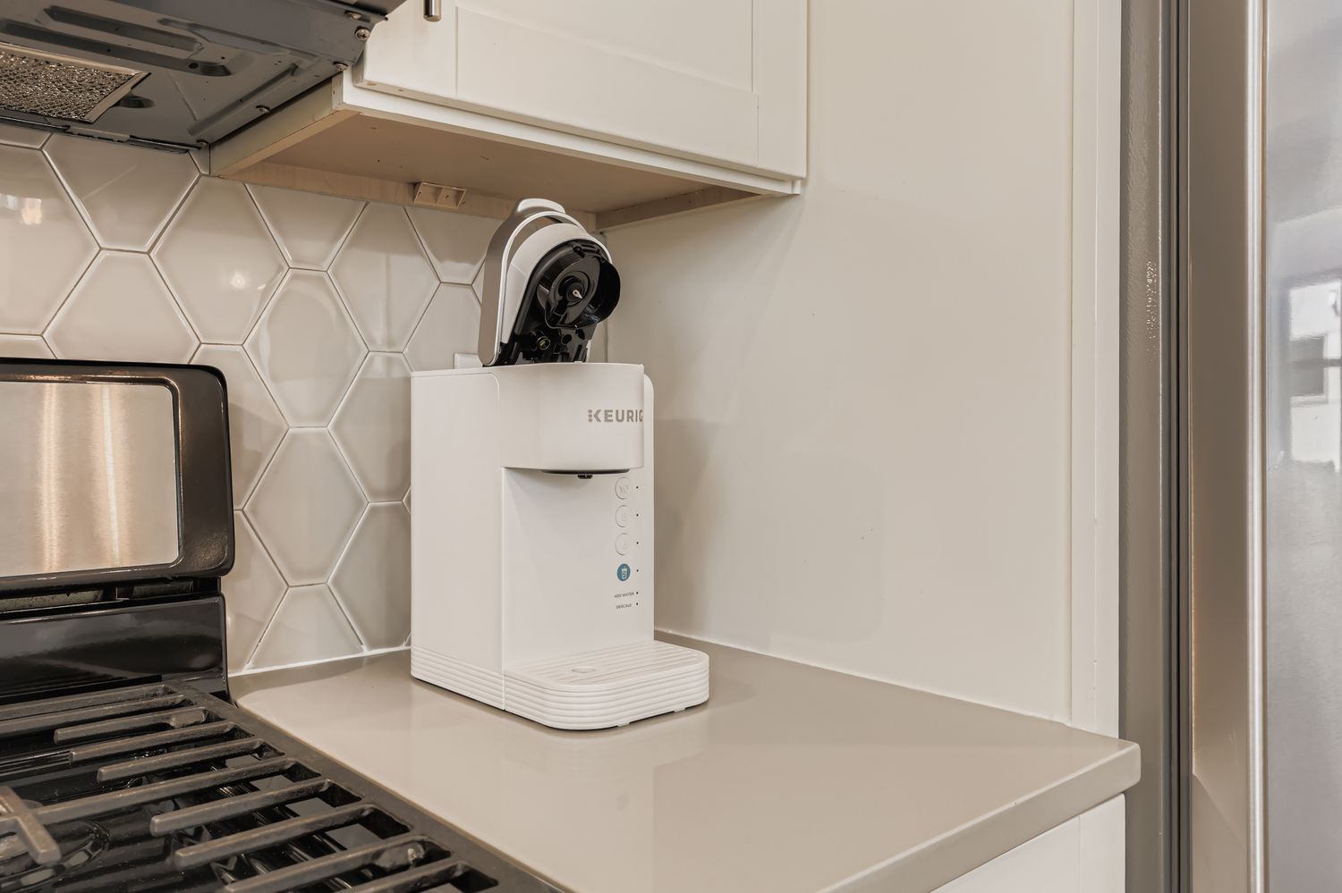 A sleek, modern kitchen with clean lines and stylish hexagonal backsplash awaits your culinary adventures, complete with premium appliances and a convenient coffee maker for your morning routine.