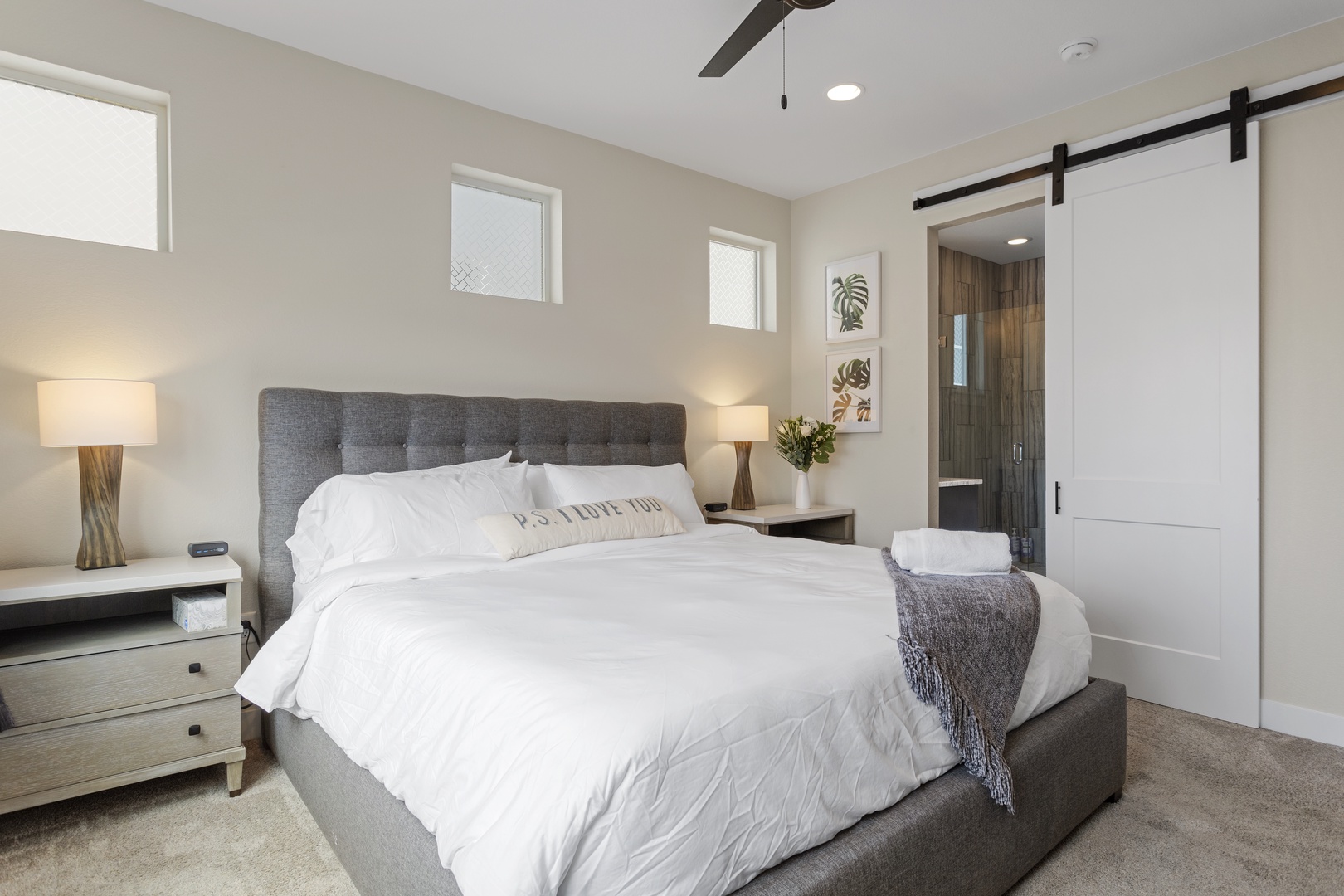 Sink into this plush king bed with crisp white linens and warm lighting. Your private ensuite awaits behind stylish barn doors.