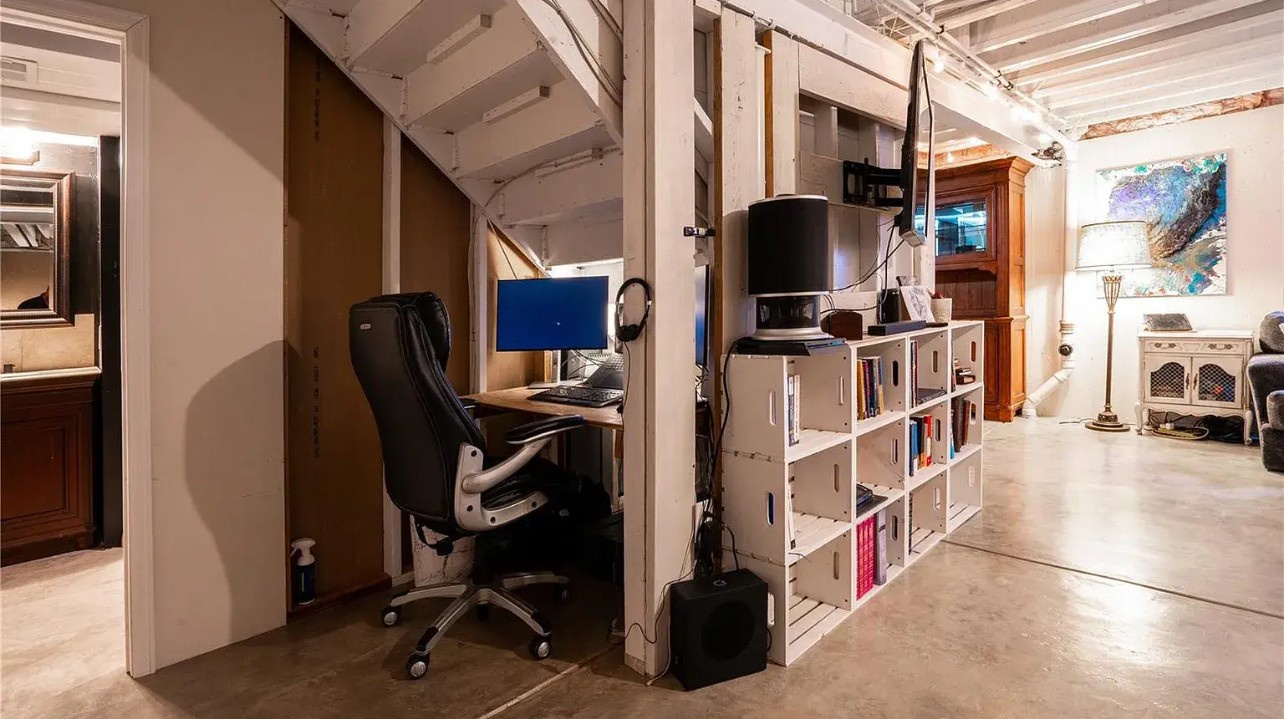 Your dedicated workspace awaits with ergonomic seating and organized shelving in this thoughtfully designed basement office area.