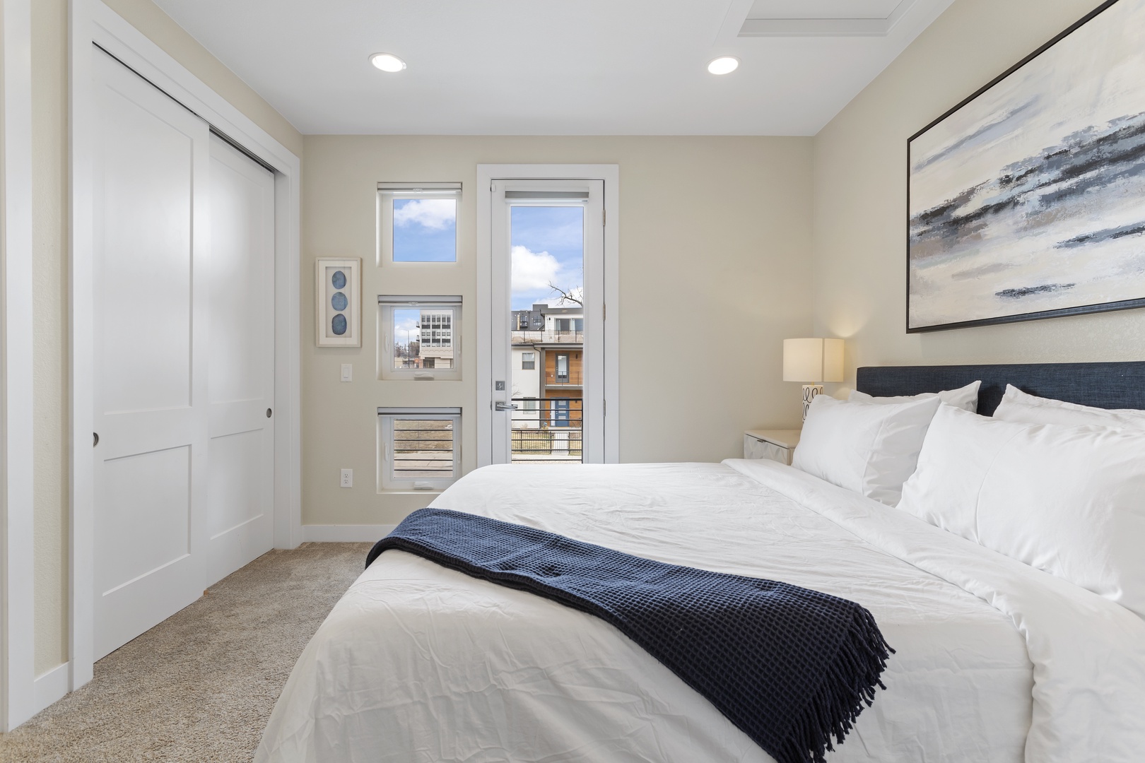 Sink into crisp white linens in your serene bedroom, where city views through French doors create a peaceful urban retreat.