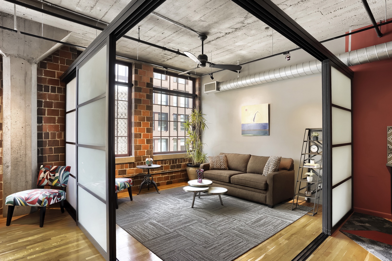 Step into your stylish urban retreat, where exposed brick meets modern comfort. Unwind on the plush sofa, enjoy natural light through industrial windows, and make yourself at home in this chic, art-filled loft space.