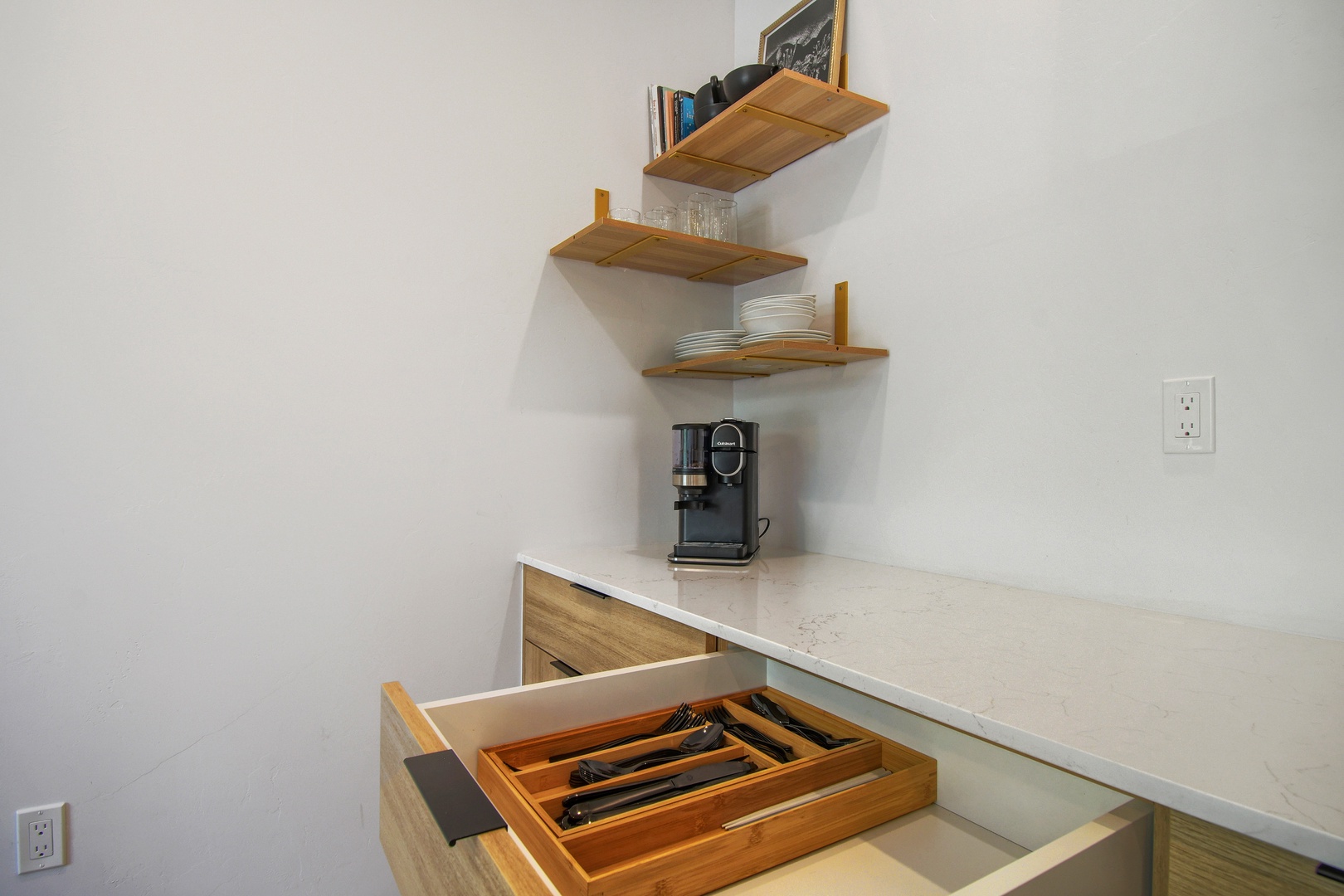 Your coffee station awaits with stylish open shelving and thoughtfully organized drawers that make your mornings effortless. Everything you need is at your fingertips in this modern kitchen corner.