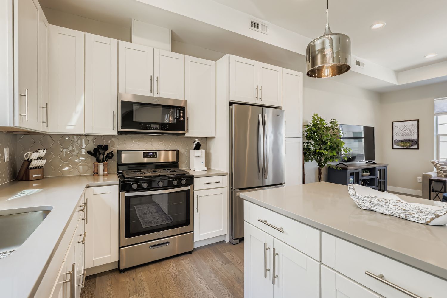 Step into your fully-equipped kitchen where cooking becomes a joy. Gleaming stainless steel appliances complement pristine white cabinetry, while natural light flows through to your comfortable living space beyond.