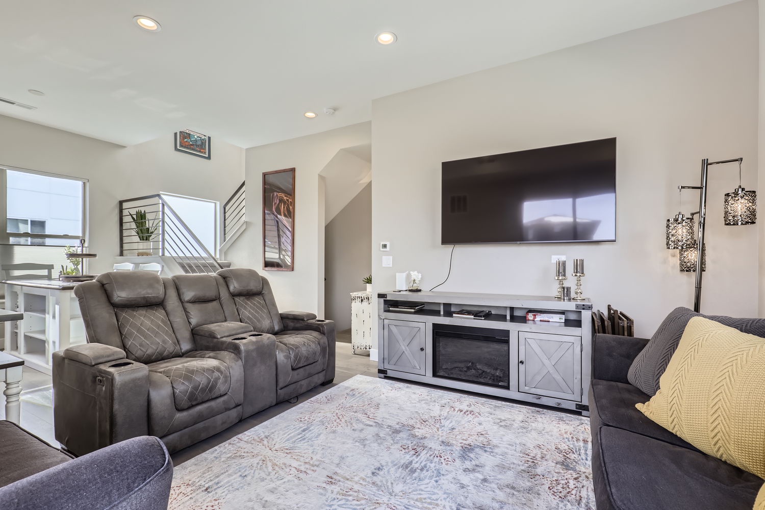 Unwind in your spacious living room with plush seating, a modern entertainment center, and warm fireplace. Natural light streams through the windows, creating a bright and welcoming space for relaxation.
