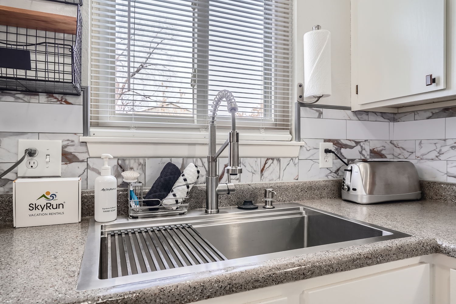 Your fully equipped kitchen features modern stainless steel fixtures and elegant marble backsplash, making meal prep a breeze while natural light streams through the window above the sink.