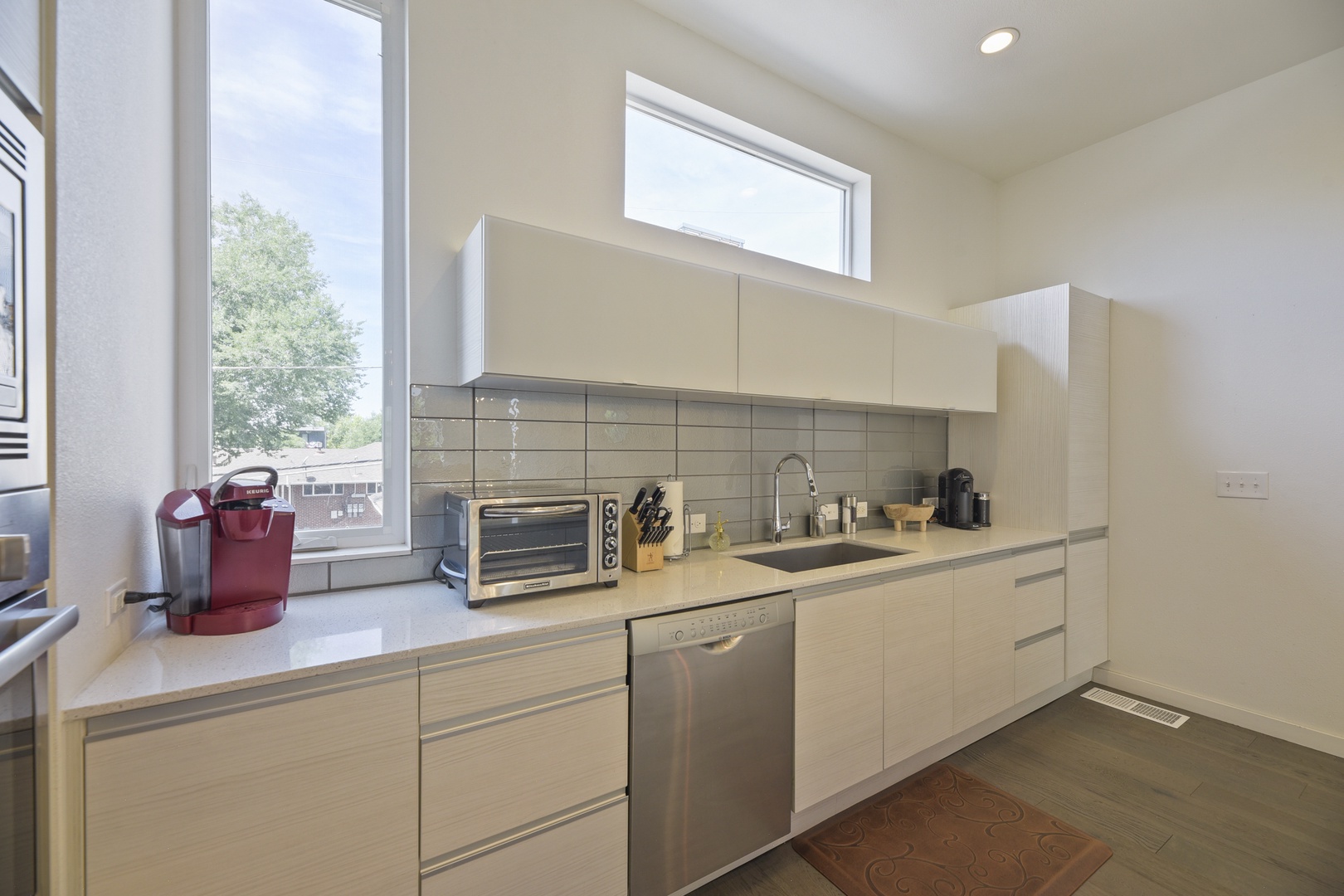 A bright, modern kitchen awaits your culinary adventures, featuring sleek cabinetry, stainless appliances, and large windows that fill the space with natural light as you prepare meals.