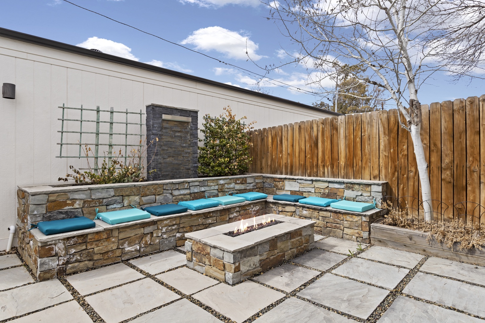 Unwind around your private stone fire pit with built-in seating and turquoise cushions in this beautifully landscaped courtyard oasis.