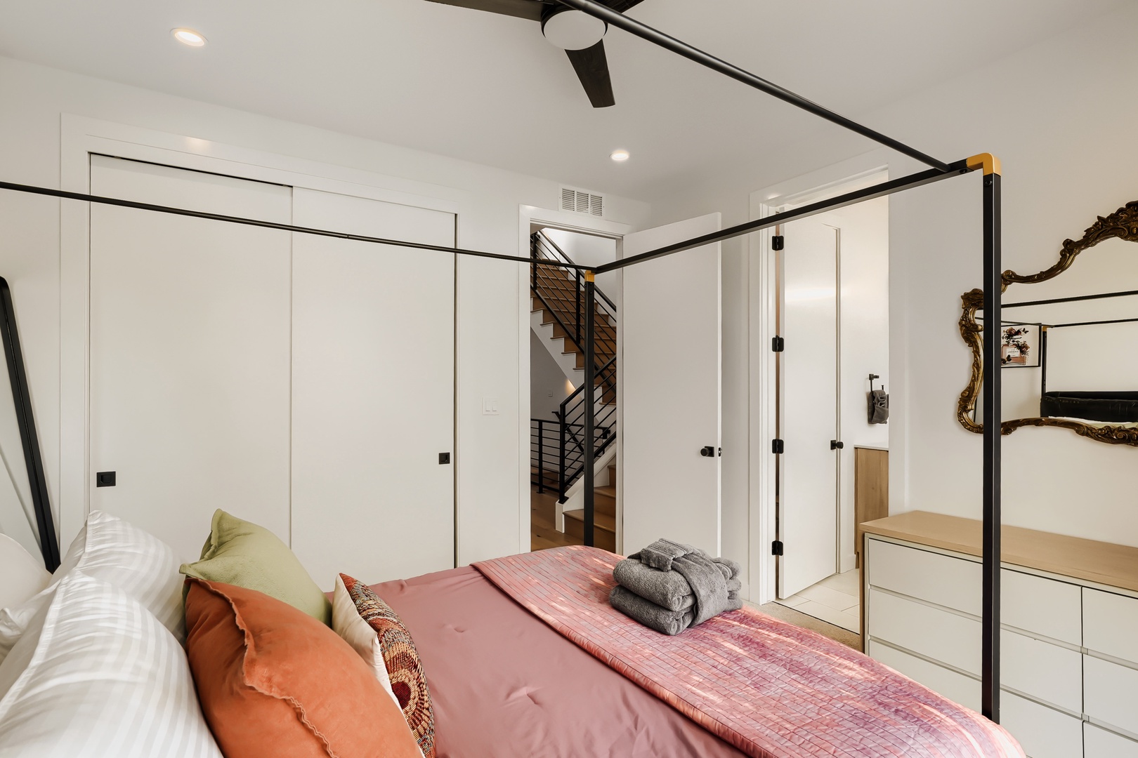 Unwind in your airy bedroom, where a sleek canopy bed and warm textiles invite restful nights, while a striking sculptural mirror adds artistic flair to your private retreat.
