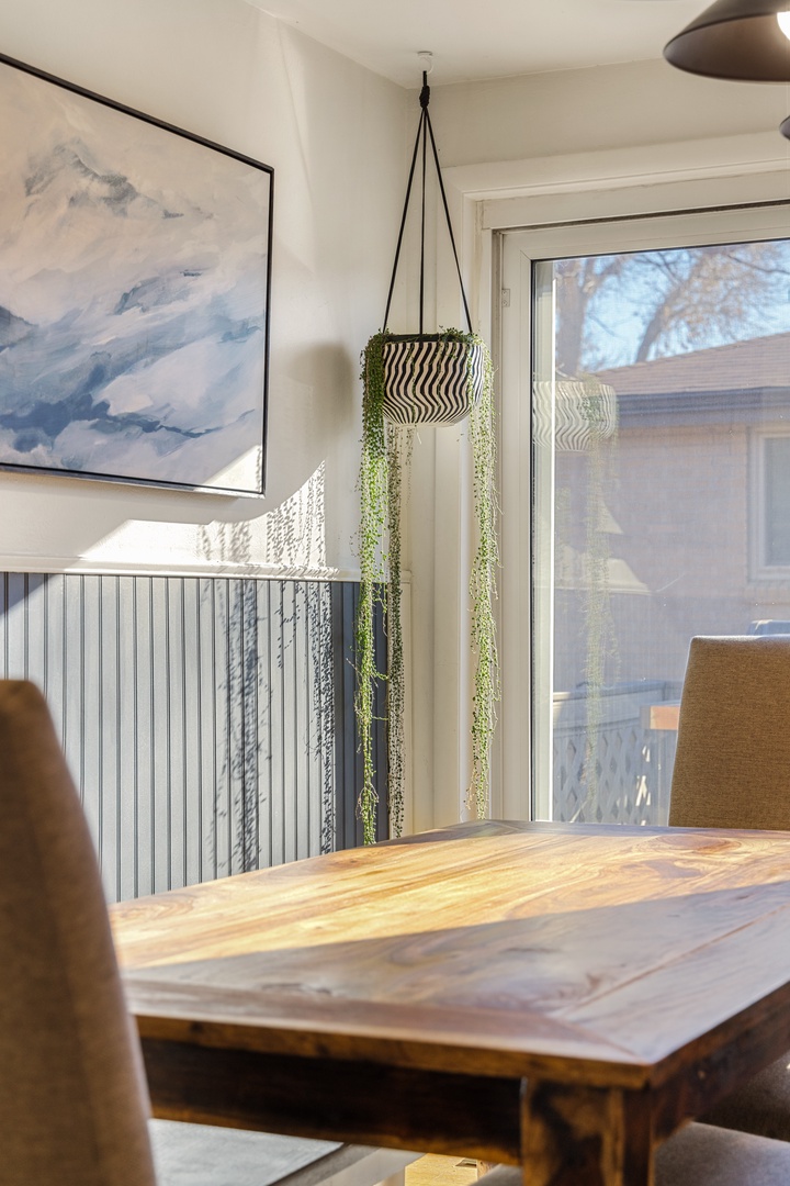 Your dining space blends warmth with style—natural wood meets modern art while fresh greenery adds life to your meals.