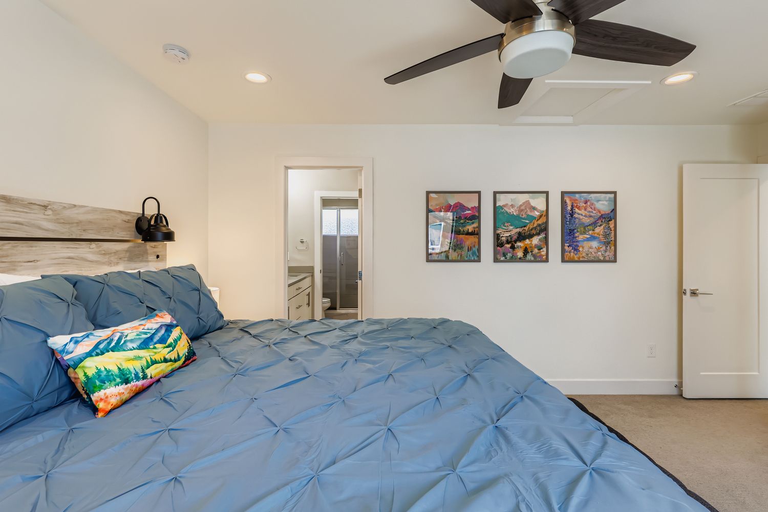 Rest easy in your spacious bedroom with plush bedding, a gentle ceiling fan overhead, and an en-suite bathroom just steps away for your convenience.