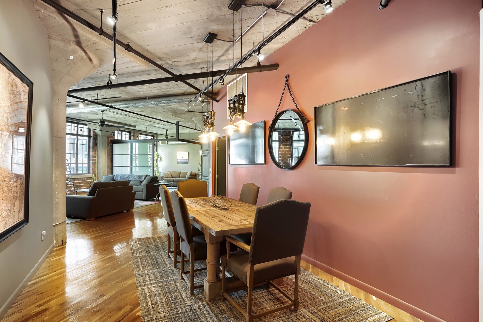 Gather around the handsome wood dining table where memorable meals unfold. Industrial-chic lighting and warm hardwood floors create an inviting atmosphere that flows seamlessly into your spacious living area.