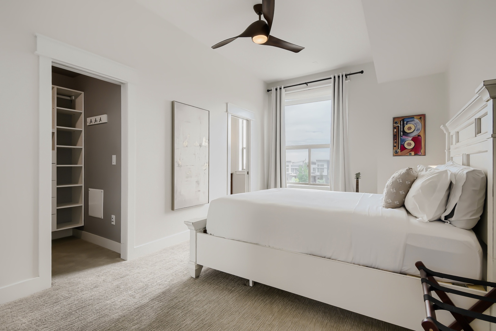 Drift off in this serene bedroom with crisp white linens, modern décor, and a ceiling fan to keep you comfortable. Gentle natural light streams through the window, inviting peaceful mornings and restful nights.