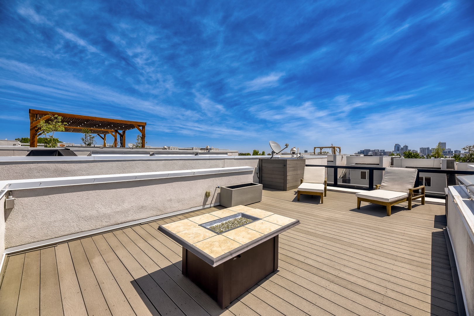 Spacious rooftop deck with a fire pit, pergola, and city skyline views—an ideal spot for unwinding under open skies.