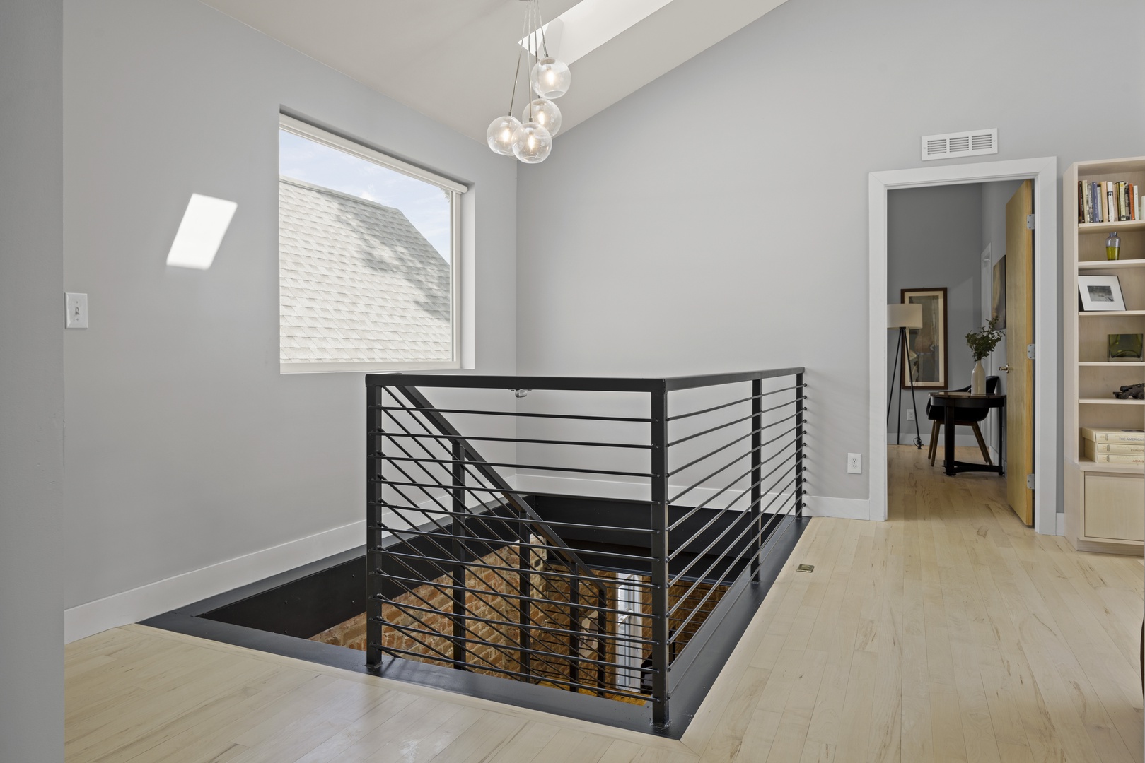 Your stylish upper-level landing features modern design with sleek railings and warm wood floors, creating an elegant transition space.