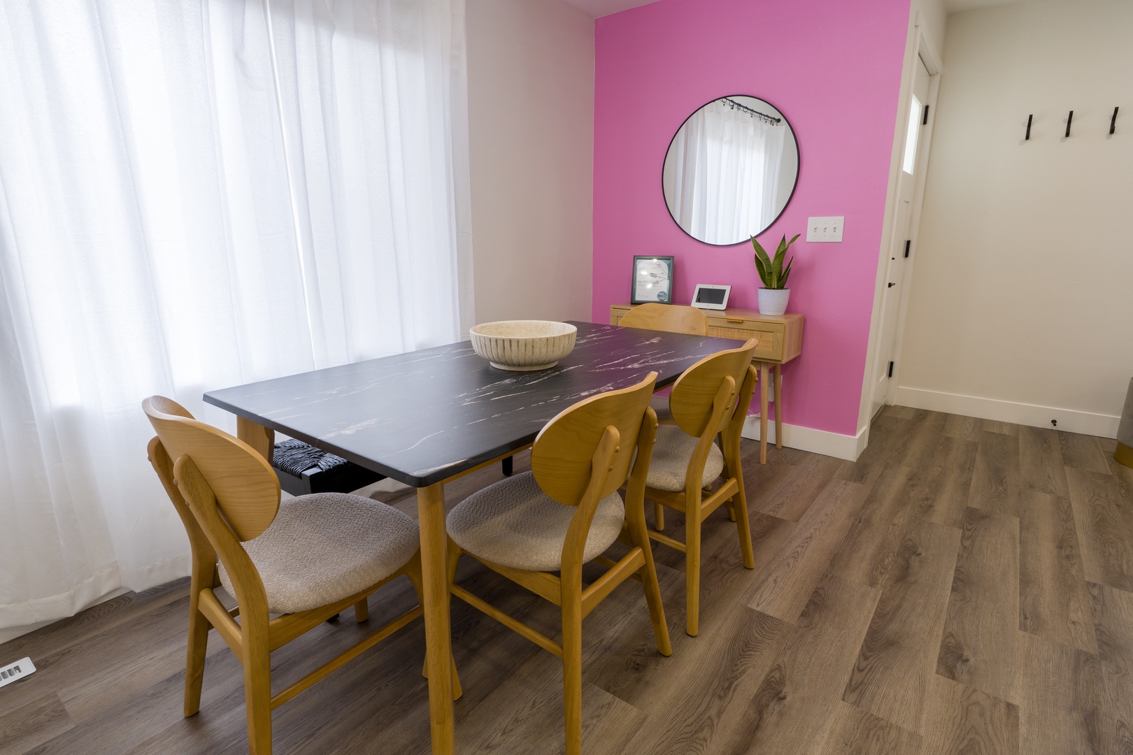 Your stylish dining space features a sleek dark table with warm wood chairs, where morning coffee and evening meals become special moments.