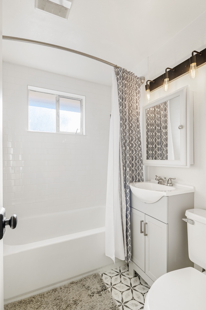 Refresh in your bright, modern bathroom featuring stylish fixtures, a relaxing tub, and beautiful geometric details.