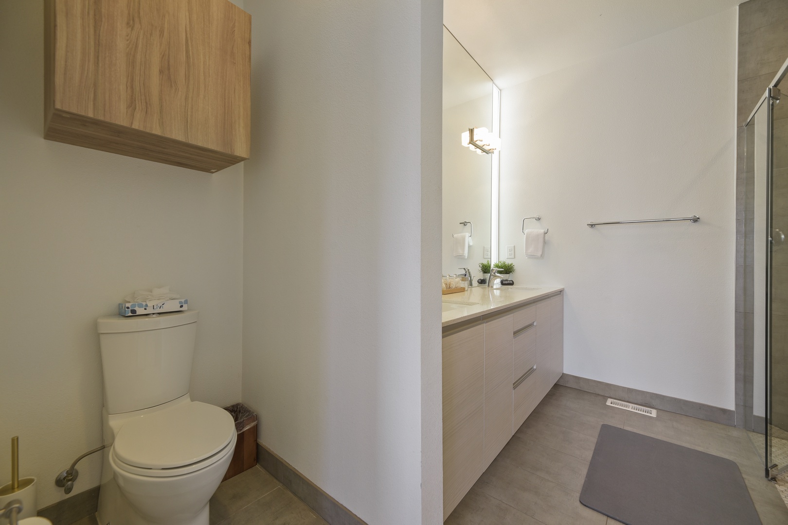 Your private bathroom offers a fresh, modern design with warm wood tones, a sleek vanity, and all the essentials for a comfortable stay.