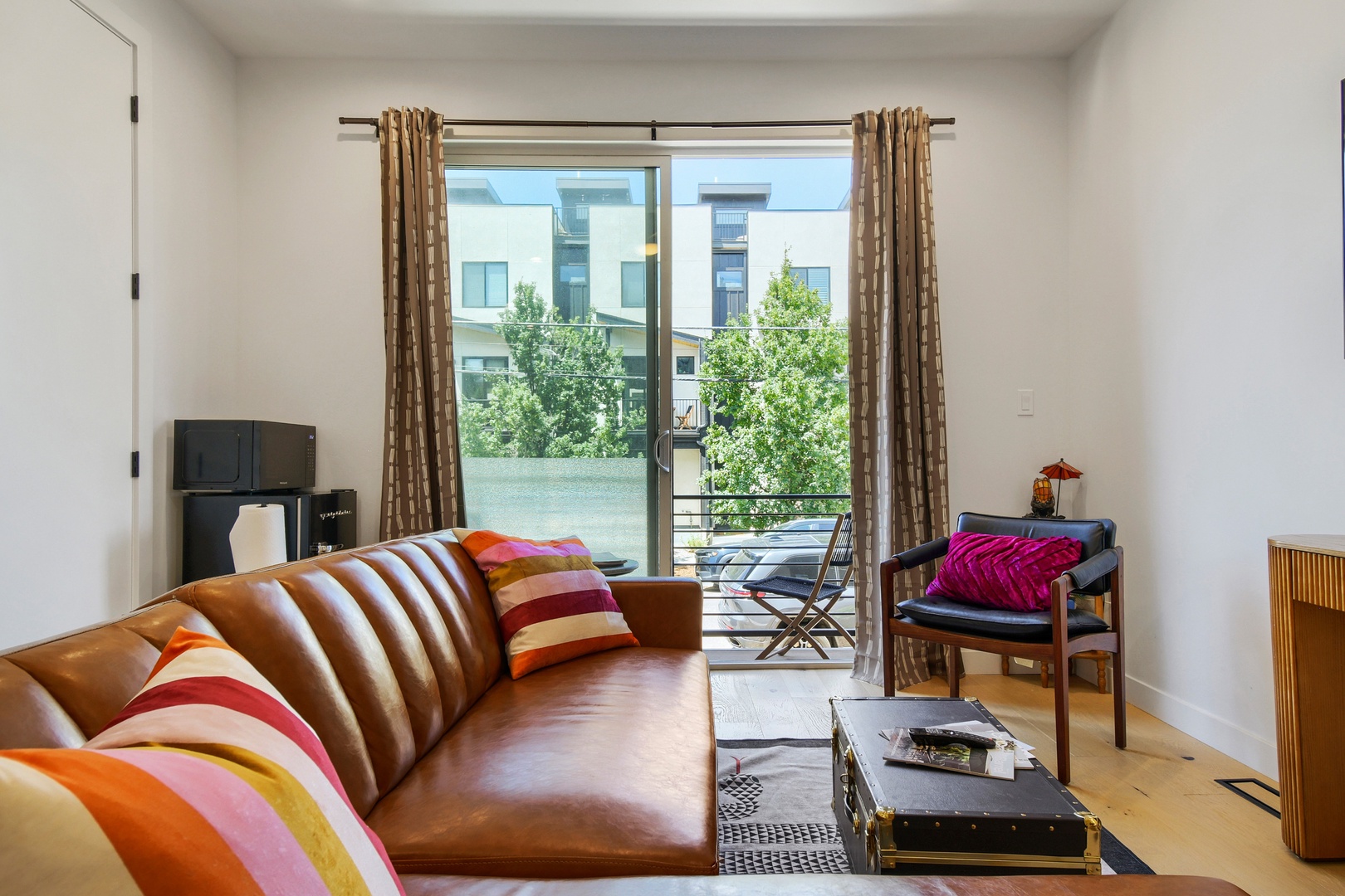 Sink into the vibrant leather sofa and let natural light pour in through your private balcony doors. The bold colors and modern style create a cheerful space where you can truly unwind.