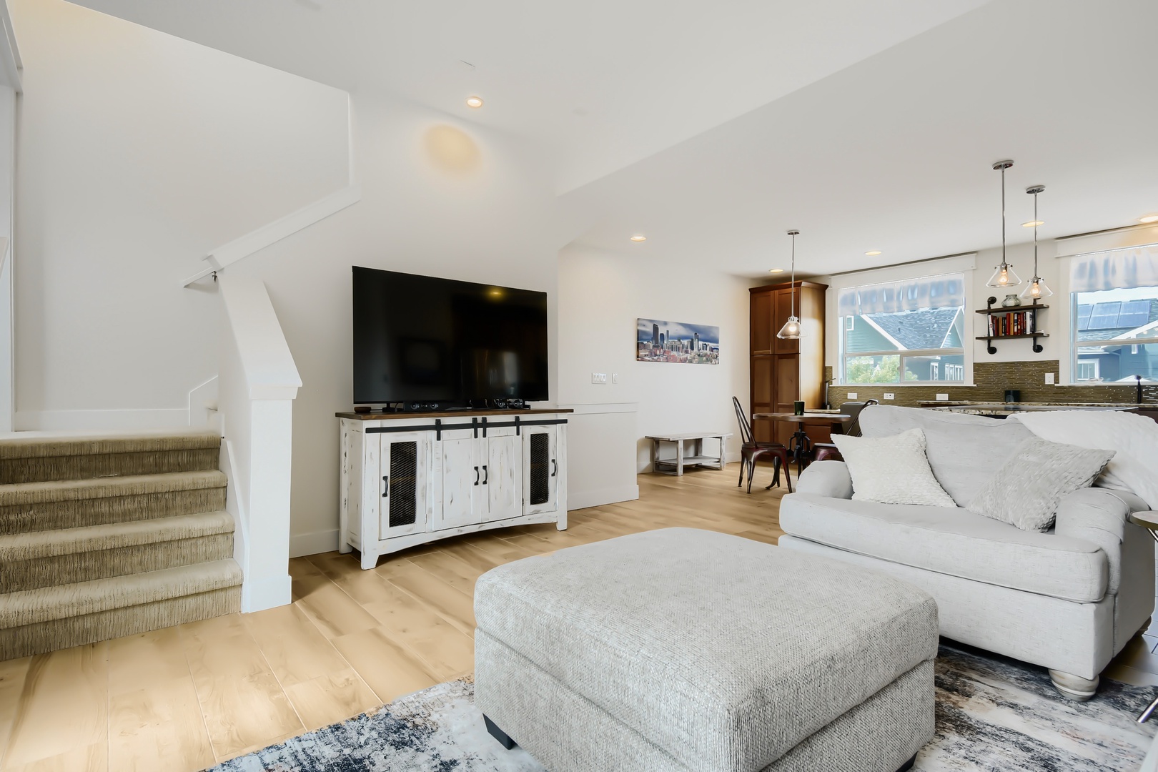 Sink into the plush sofa and enjoy your favorite shows on the big screen, with the inviting open-concept space flowing seamlessly into the kitchen and dining area—perfect for relaxing together.
