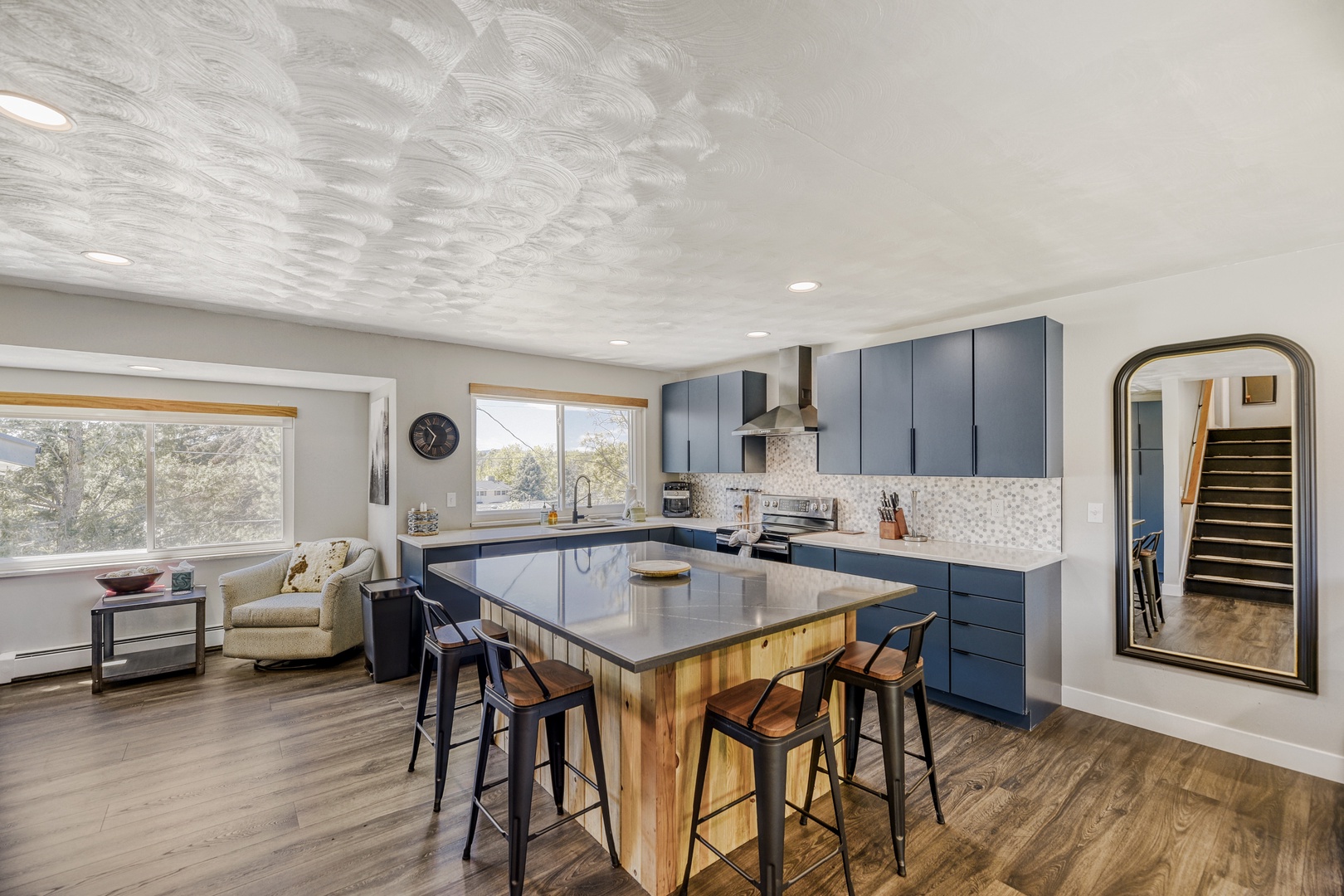 Picture yourself preparing meals in this stunning modern kitchen, with sleek blue cabinetry, a spacious island perfect for gathering, and natural light streaming through generous windows overlooking peaceful scenery.