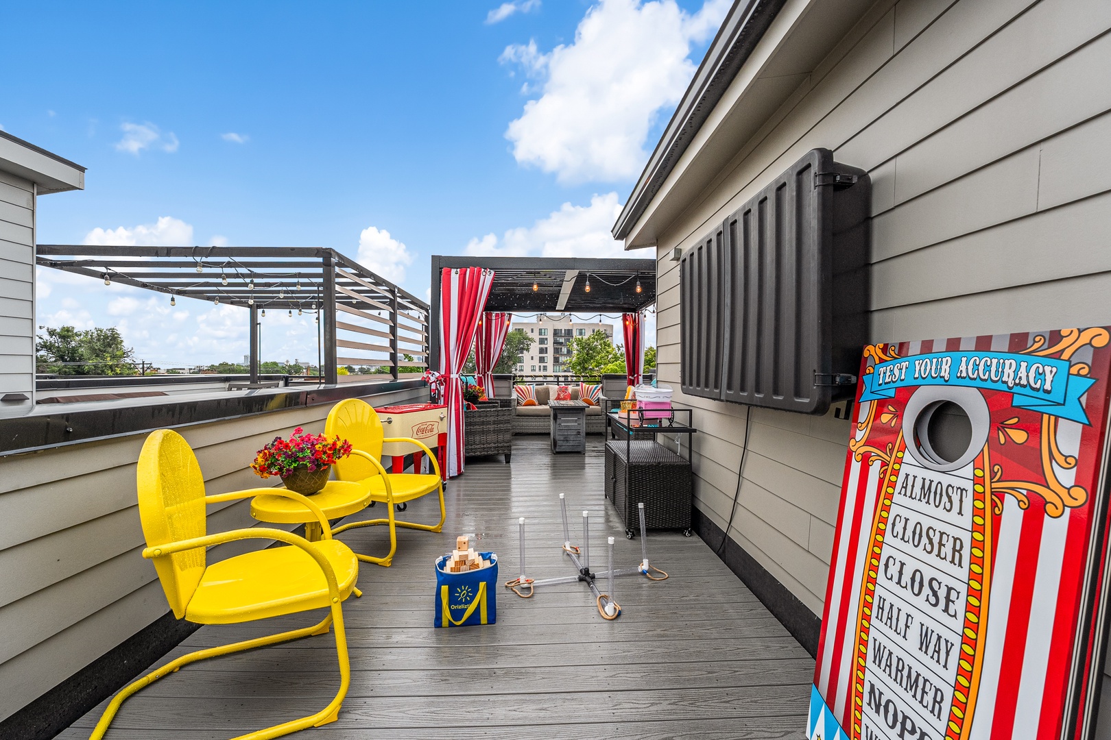 Relax on the rooftop deck where vibrant seating and playful touches create a fun outdoor retreat with blue skies and city views.