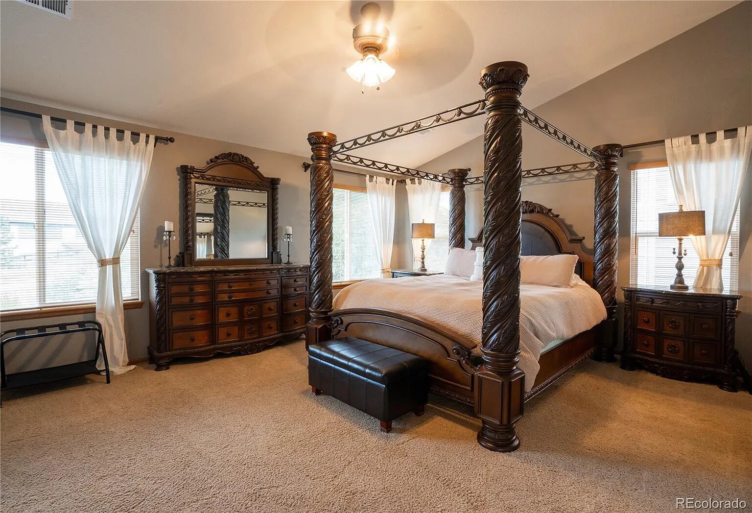 Drift off in this elegant four-poster bed with ornate columns and matching dark wood furnishings creating your perfect romantic retreat.