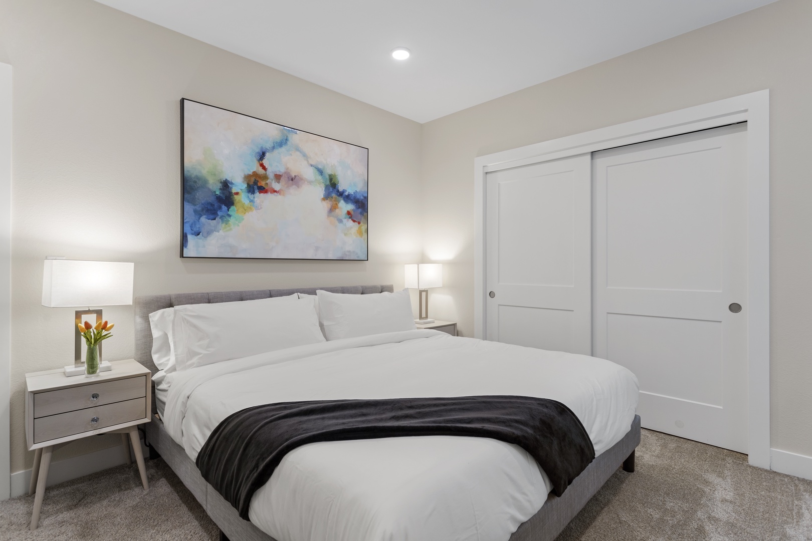 Sink into crisp white linens in your serene bedroom, where soft lighting and modern artwork create the perfect retreat.